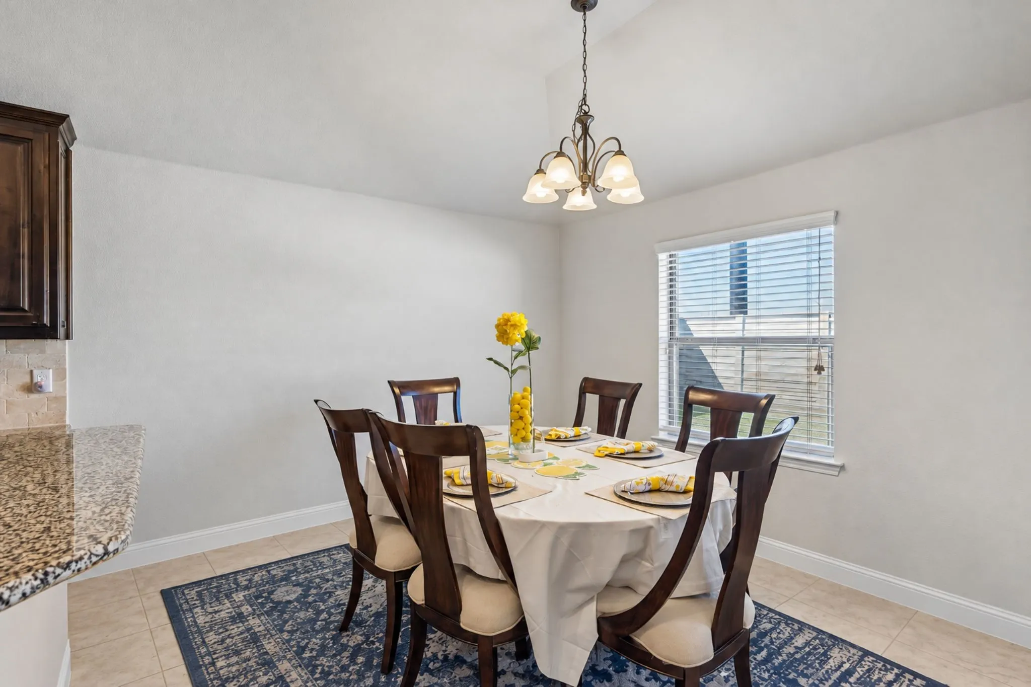 Recessed lighting, tiled flooring, built-in cabinetry, granite-look countertop, and a window with blinds