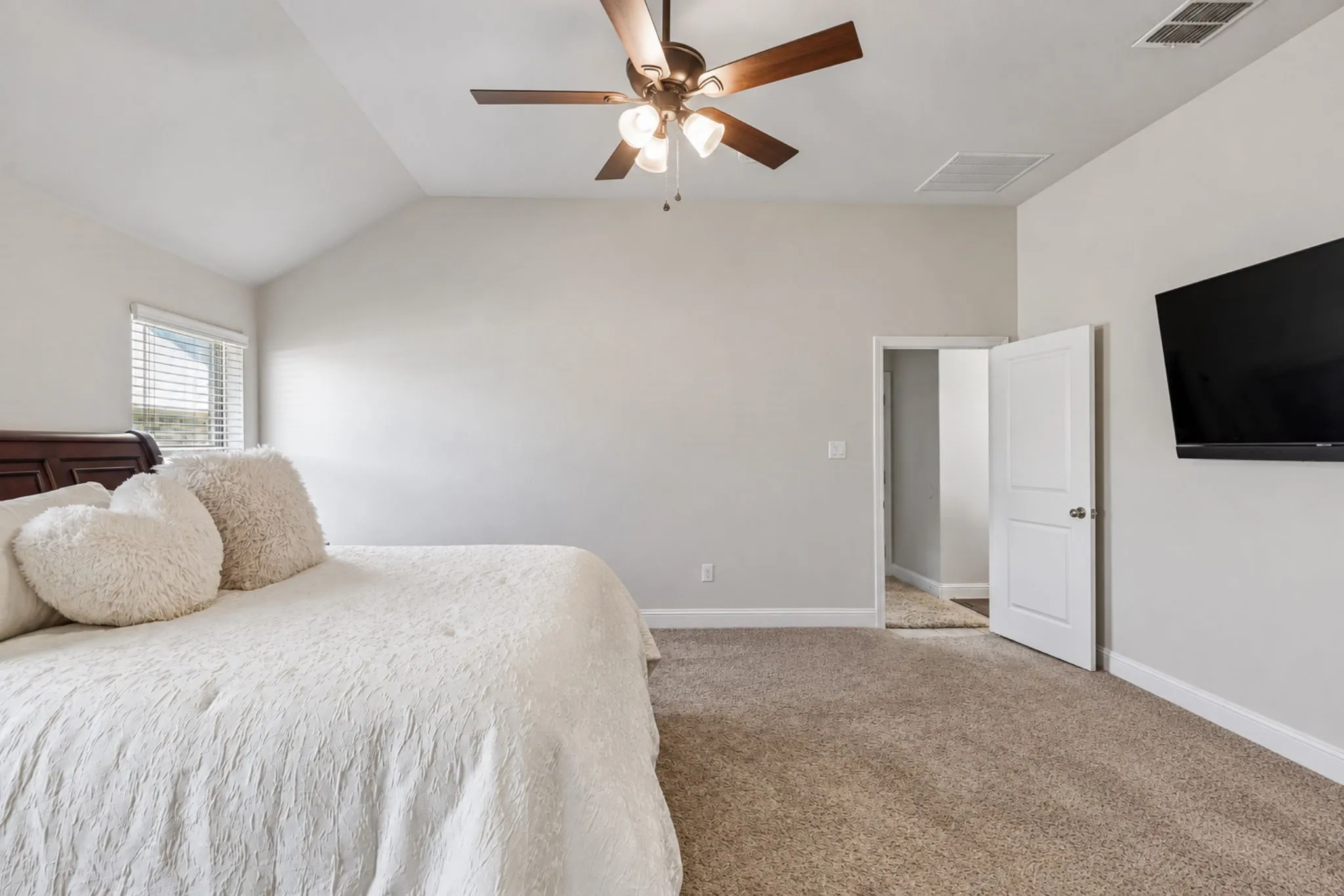 Vaulted ceiling, carpet flooring, window with blinds, ceiling fan with lighting, and a paneled door