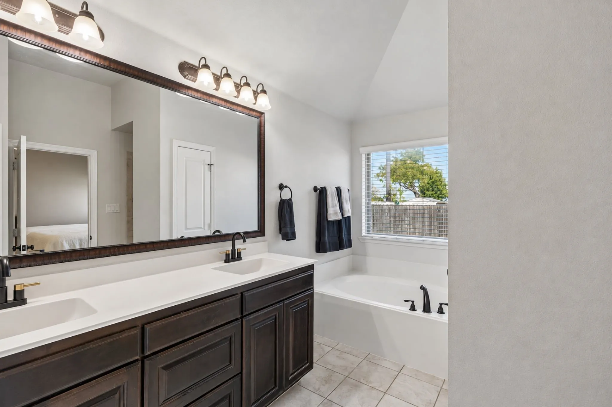 Double vanity with white countertops, dark wood cabinetry, and dual undermount sinks