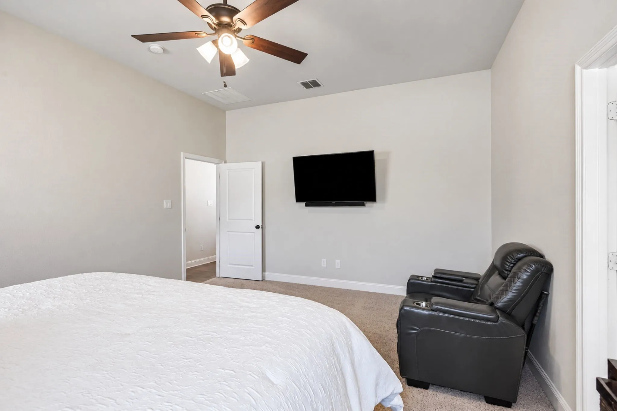 Recessed ceiling fan with wood-finish blades, soft carpet flooring, and a wall-mounted display