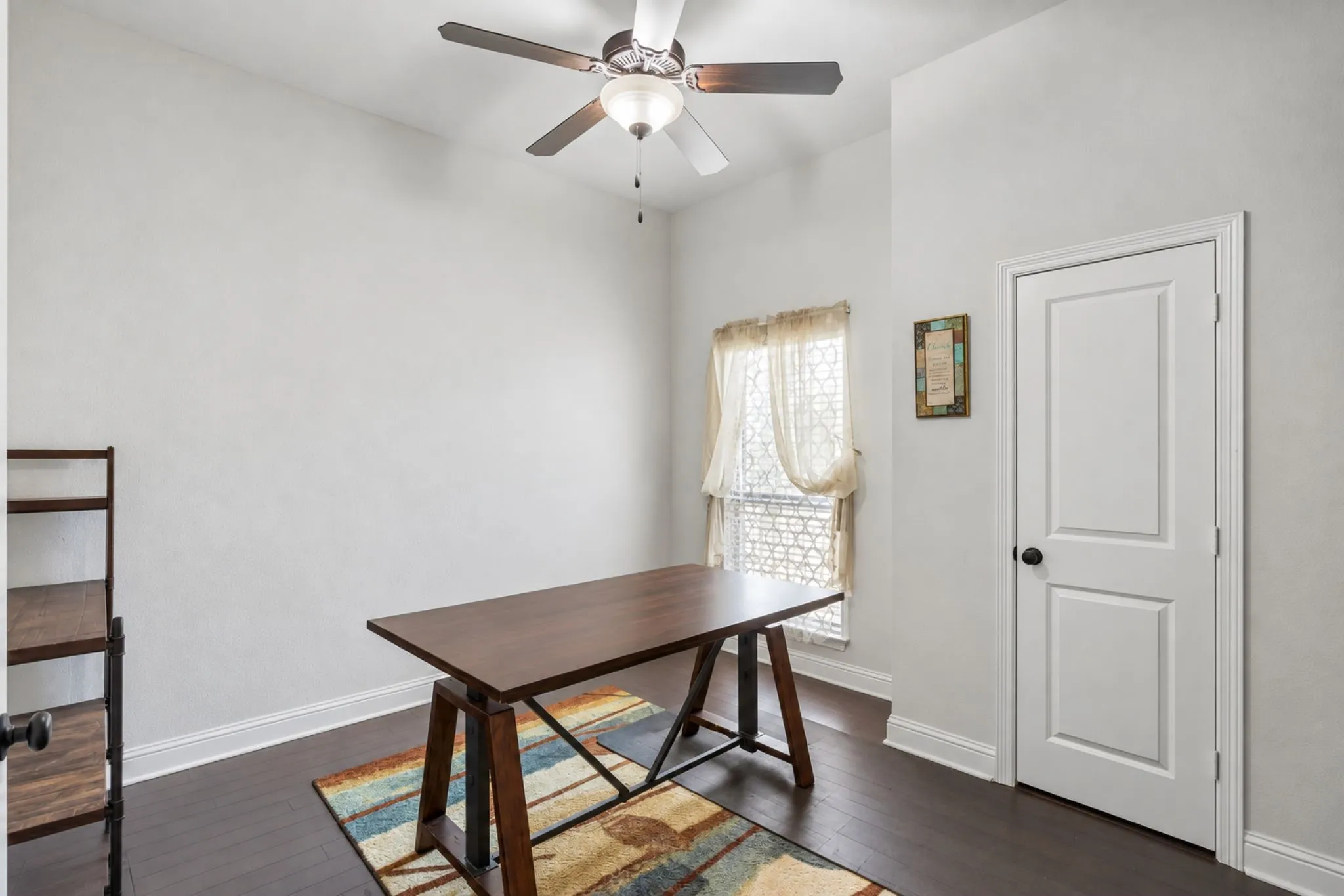 Dark wood-finish flooring with white trim, a single window, and a ceiling fan with integrated lighting