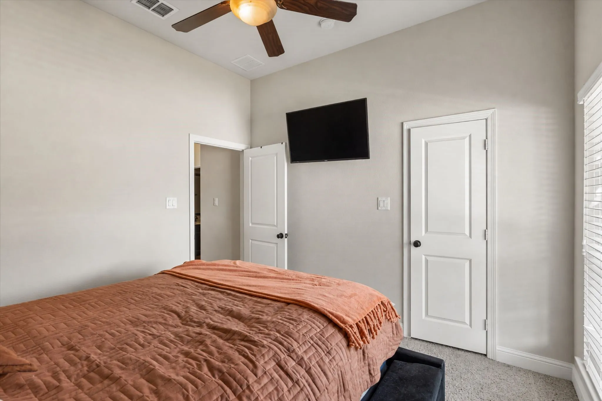Angled ceiling with a wood-finish ceiling fan, two-panel interior doors, light gray wall paint, and gray carpet