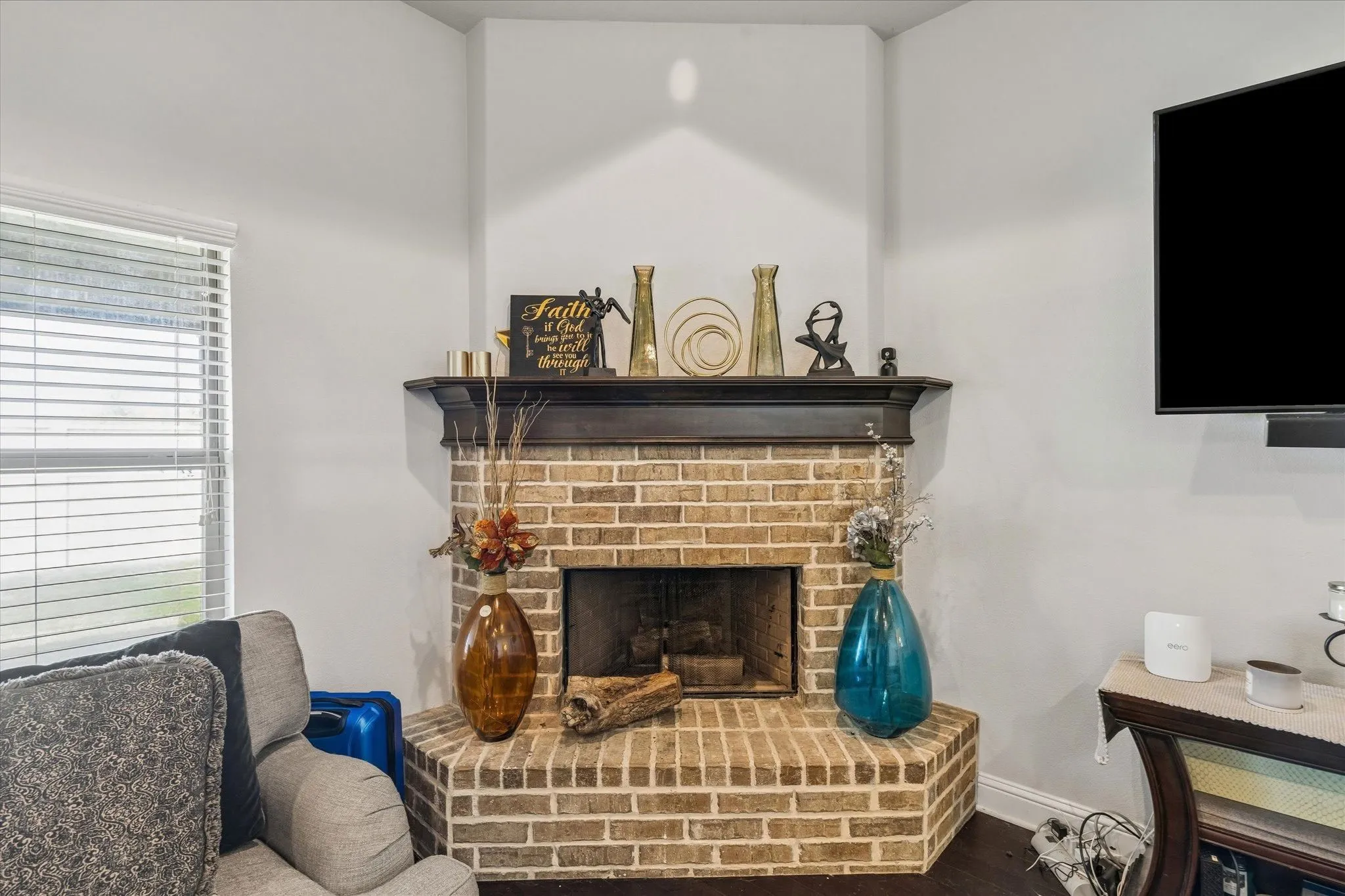 Corner brick-surround fireplace featuring a dark wood mantel and dark wood-finish flooring