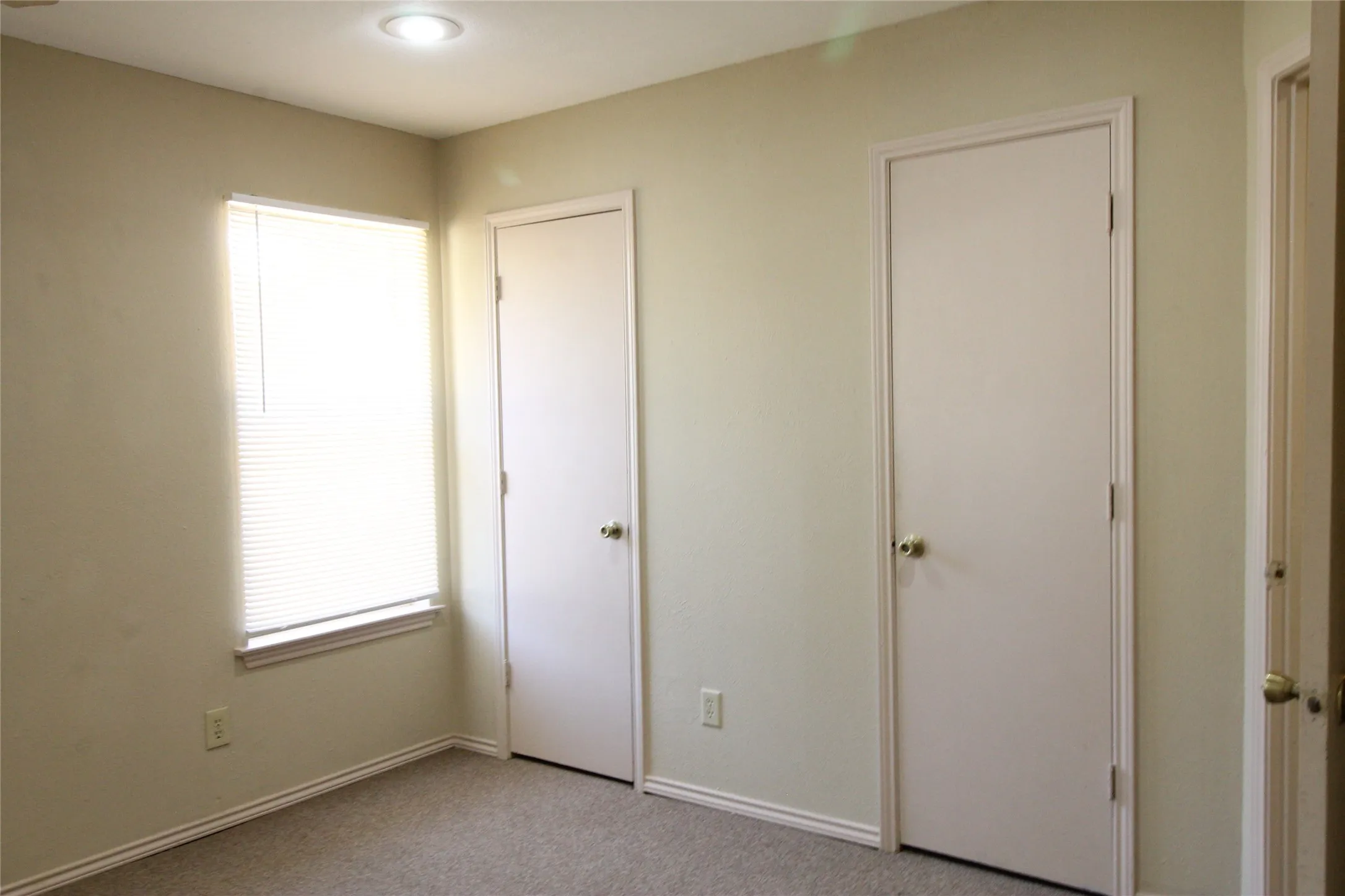 Recessed ceiling lighting, a window with horizontal blinds, and a neutral color palette