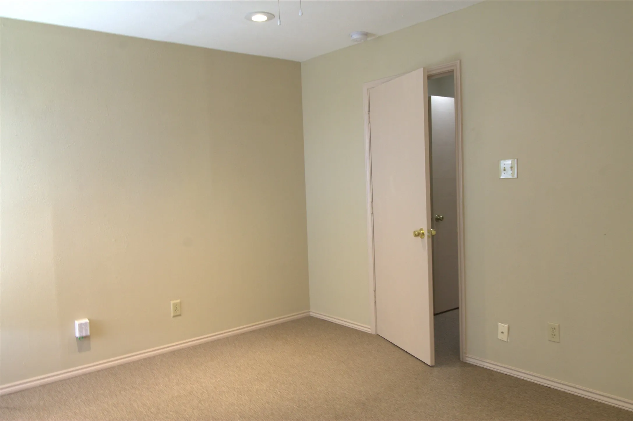 Recessed ceiling lighting, neutral carpet flooring, and a solid core interior door
