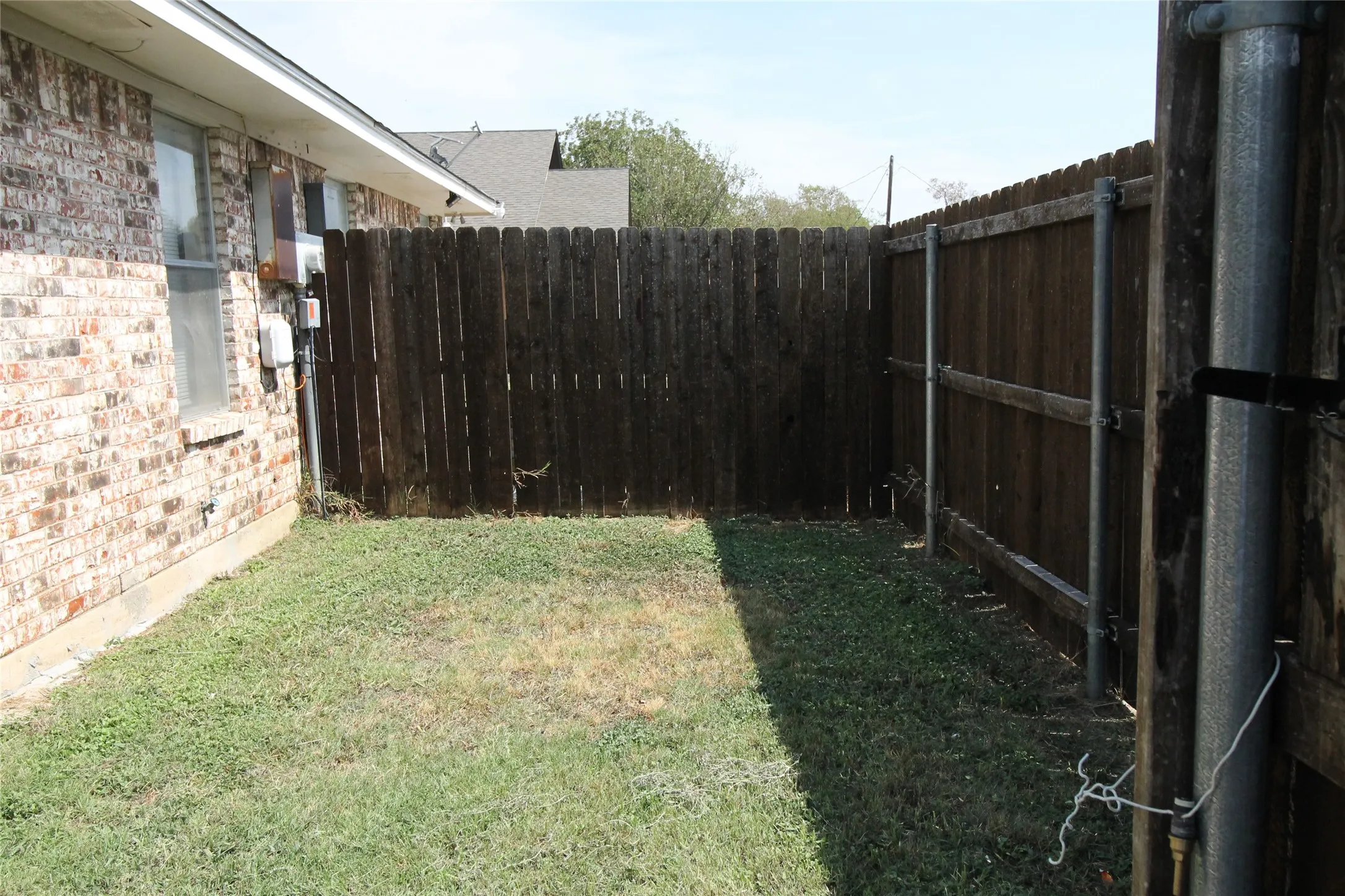 Enclosed side yard with a wood privacy fence and a brick exterior wall