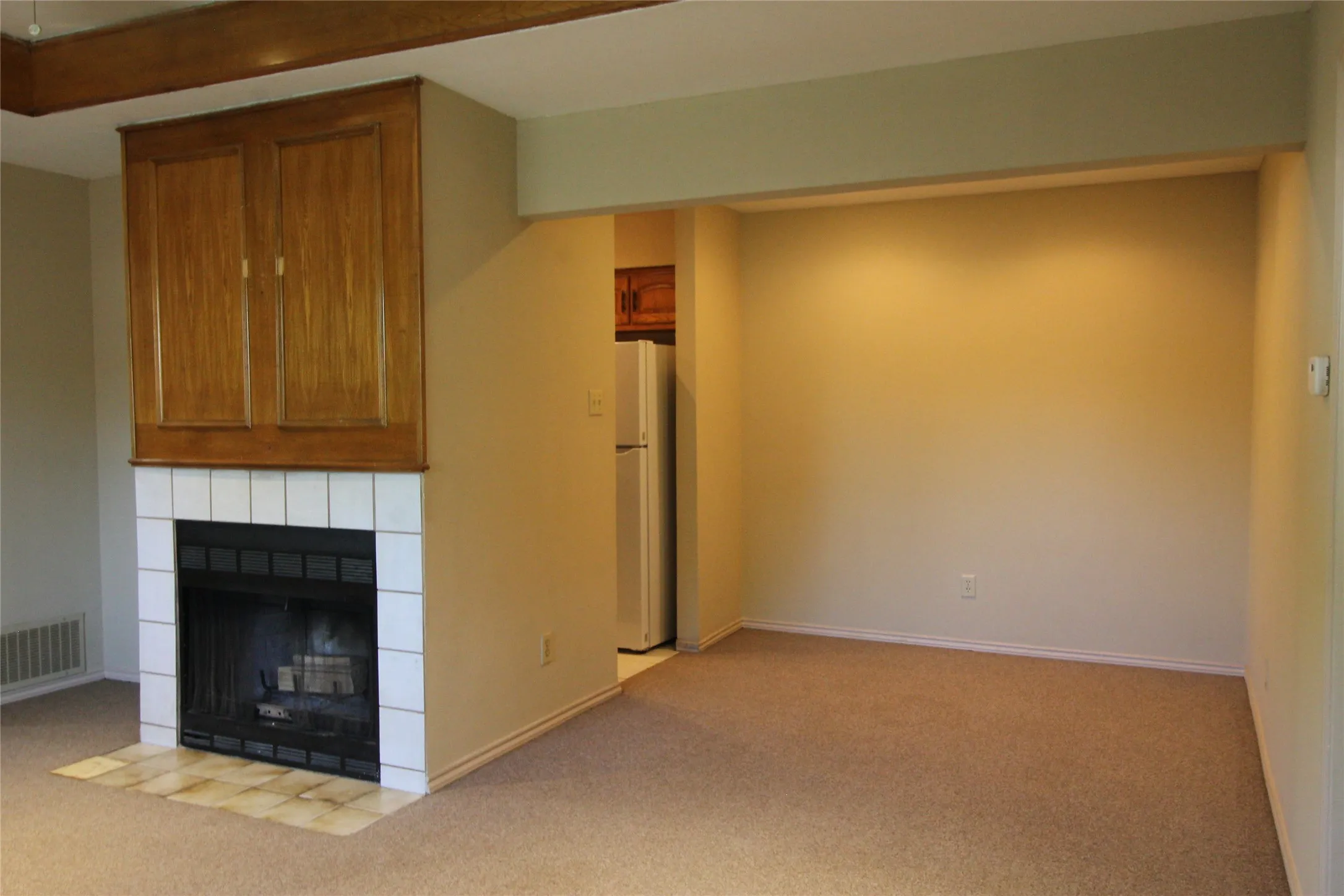 Fireplace with white tile surround and wood-finish cabinetry