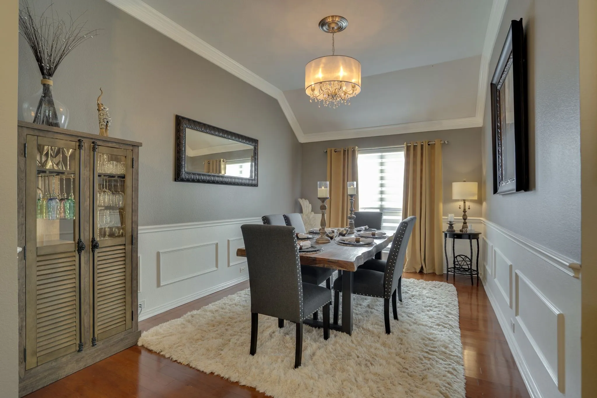 Vaulted ceiling featuring a chandelier, crown molding, wainscoting, and wood-finish flooring