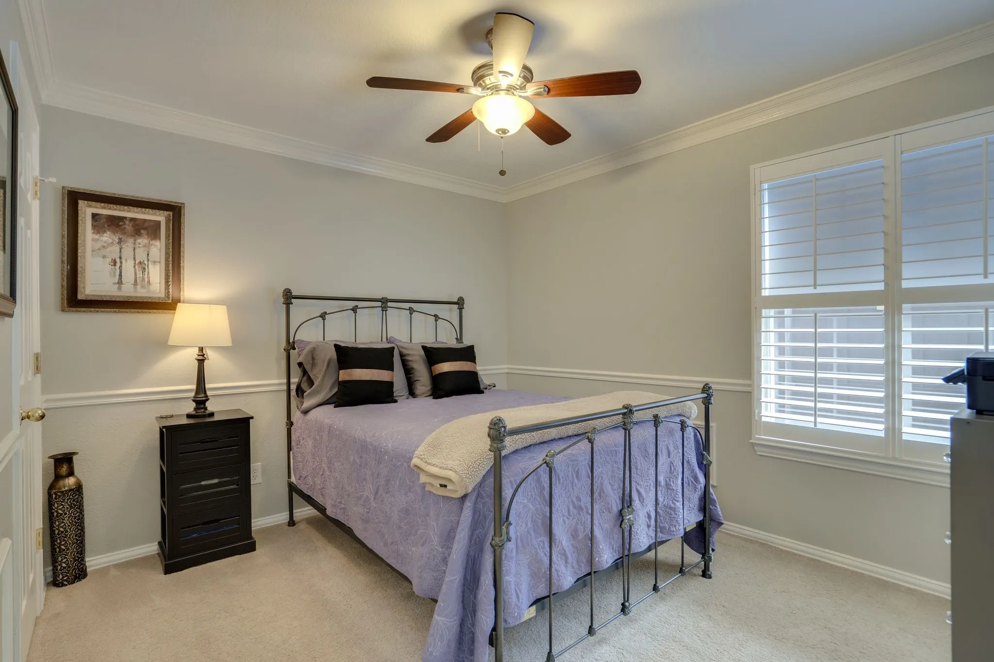 Crown molding, wainscoting, ceiling fan with integrated lighting, carpeted flooring, and plantation shutters