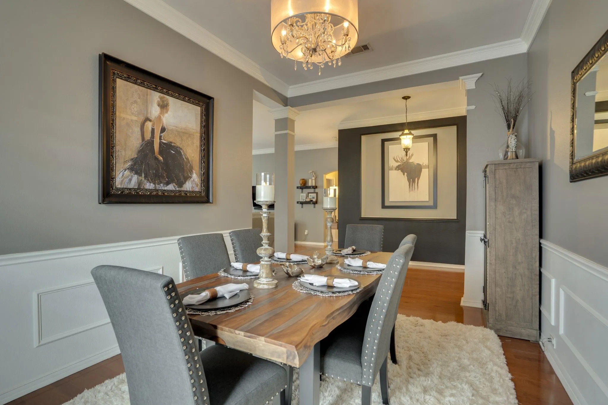 Crowned molding and wainscoting details, wood-finish flooring, and a chandelier light fixture