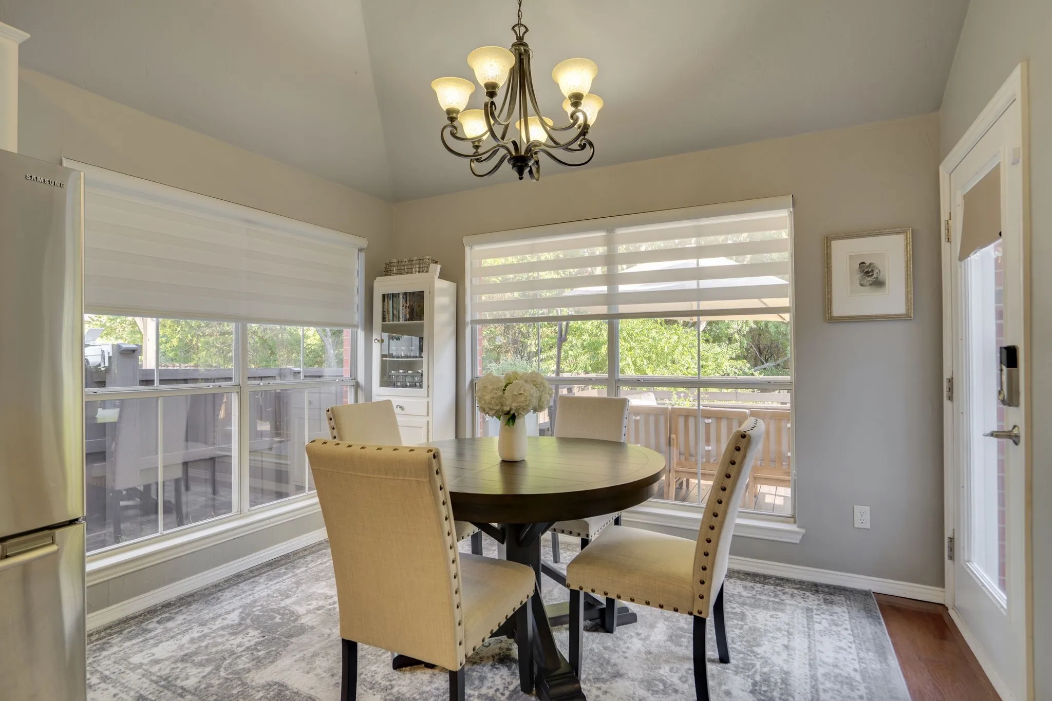 Vaulted ceiling with an iron chandelier, built-in display cabinet, and large windows
