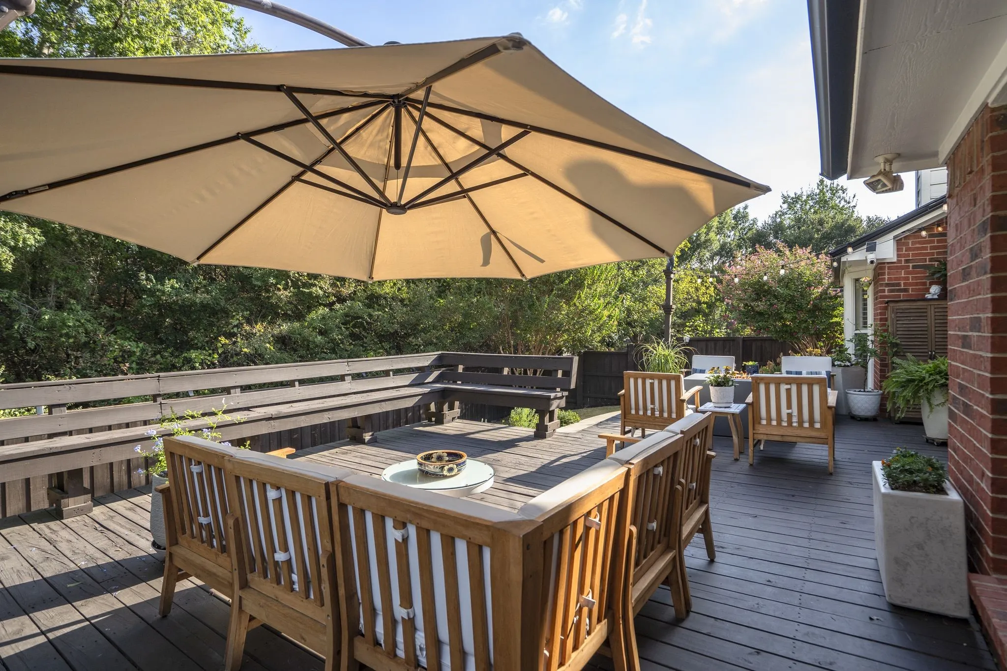 Expansive outdoor deck featuring dark wood-finish planking, integrated wood benches, and a large cantilevered umbrella