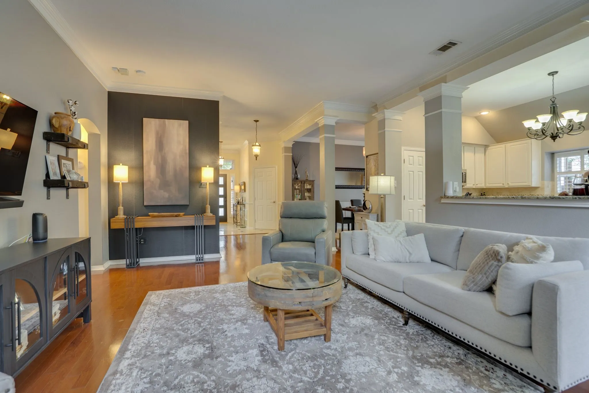 Open-concept living area featuring wood-finish flooring, crown molding, and recessed lighting