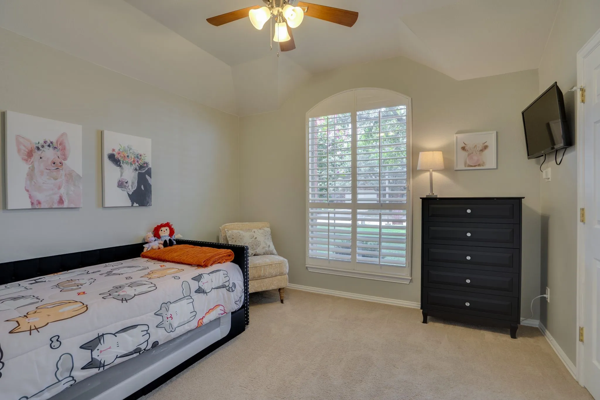 Arched window with plantation shutters, wood-finish ceiling fan, and sloped ceiling