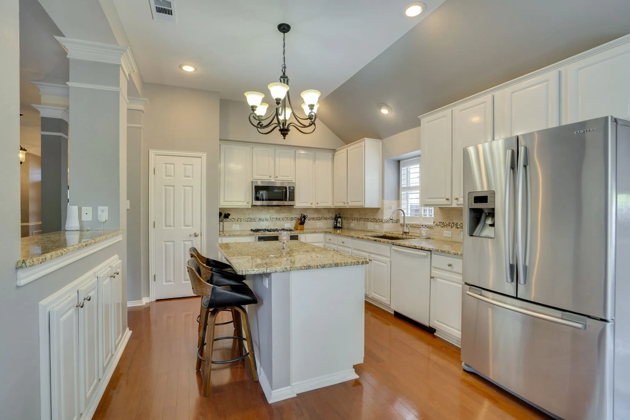 Kitchen featuring wood-finish flooring, white cabinetry, granite countertops, and stainless steel appliances