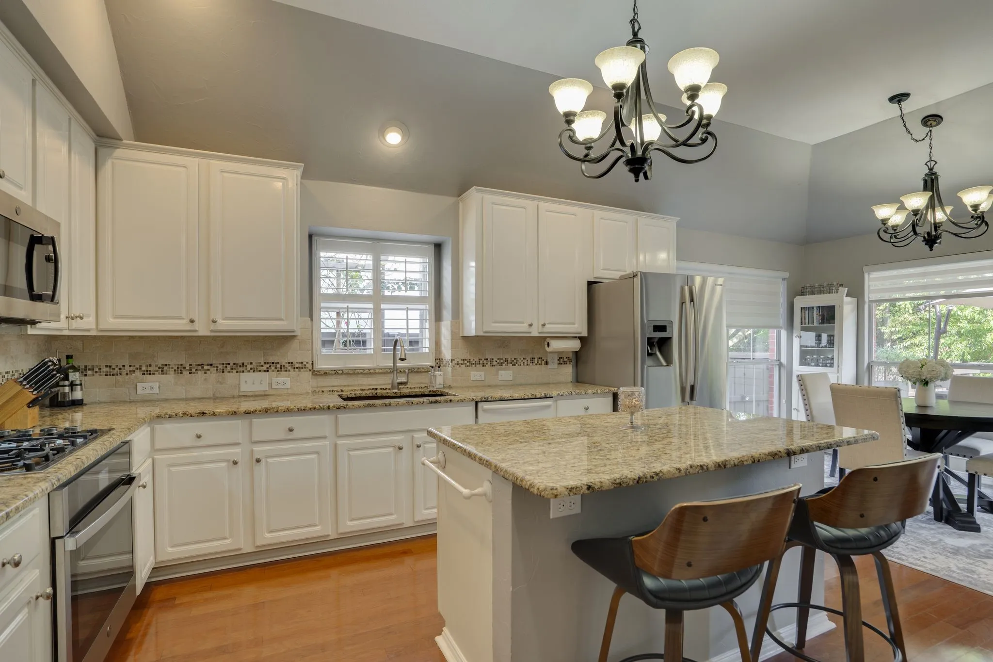 Kitchen featuring white cabinetry, stainless steel appliances, granite countertops, and wood-finish flooring