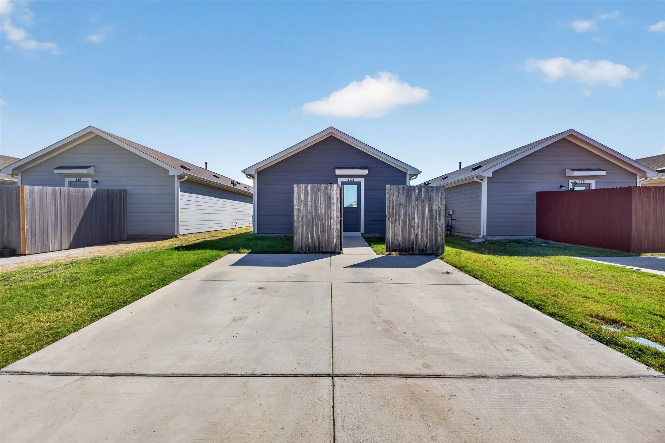 Concrete driveway leading to a fenced entry