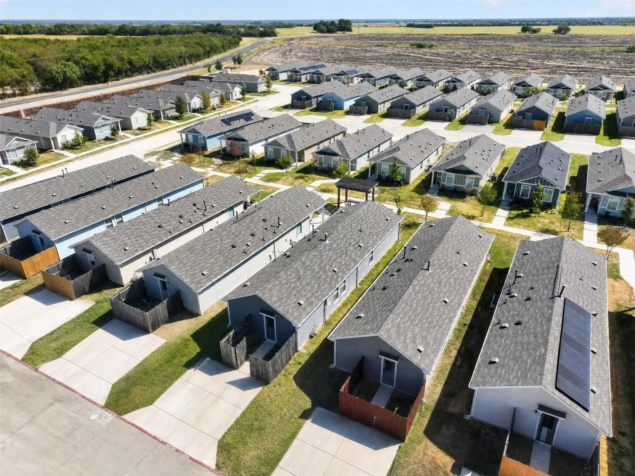 Compact residential community featuring single-story homes with shingled roofs and private outdoor areas