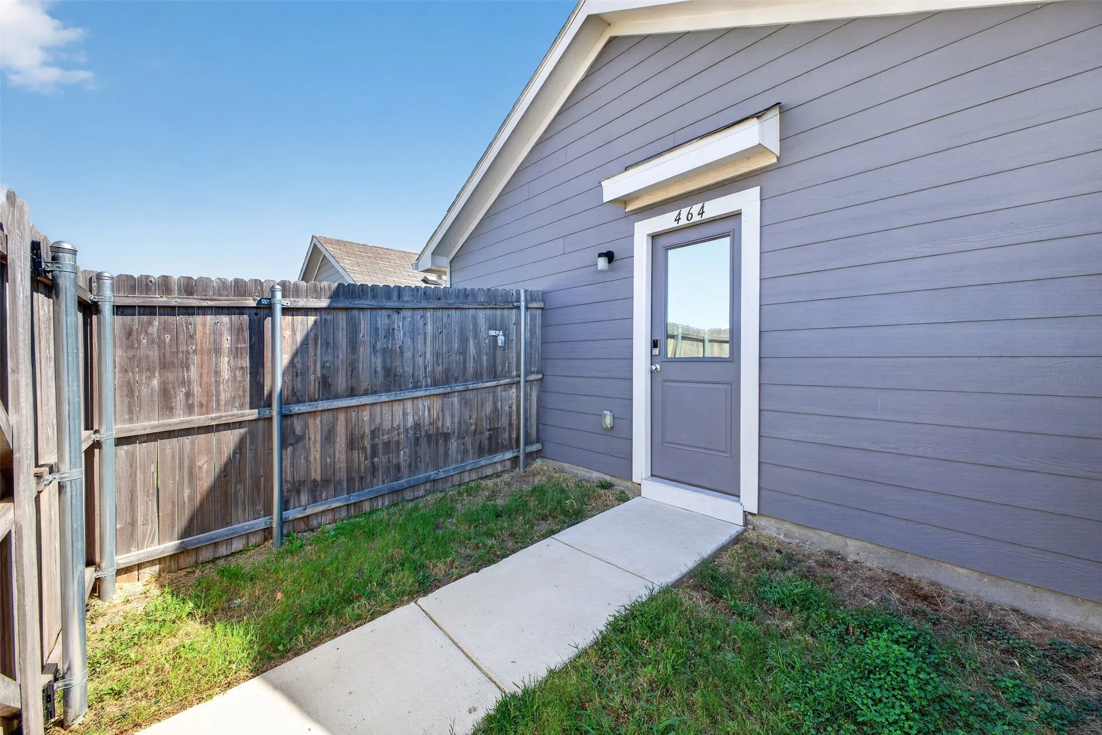 Siding exterior with a fenced perimeter and concrete walkway