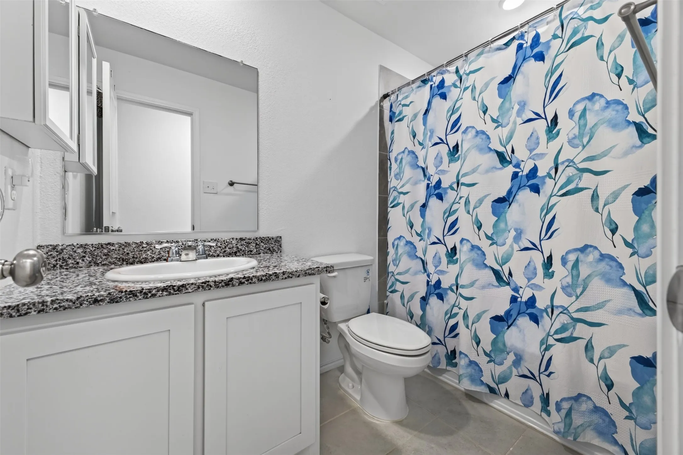 White vanity with a granite-style countertop and an undermount sink