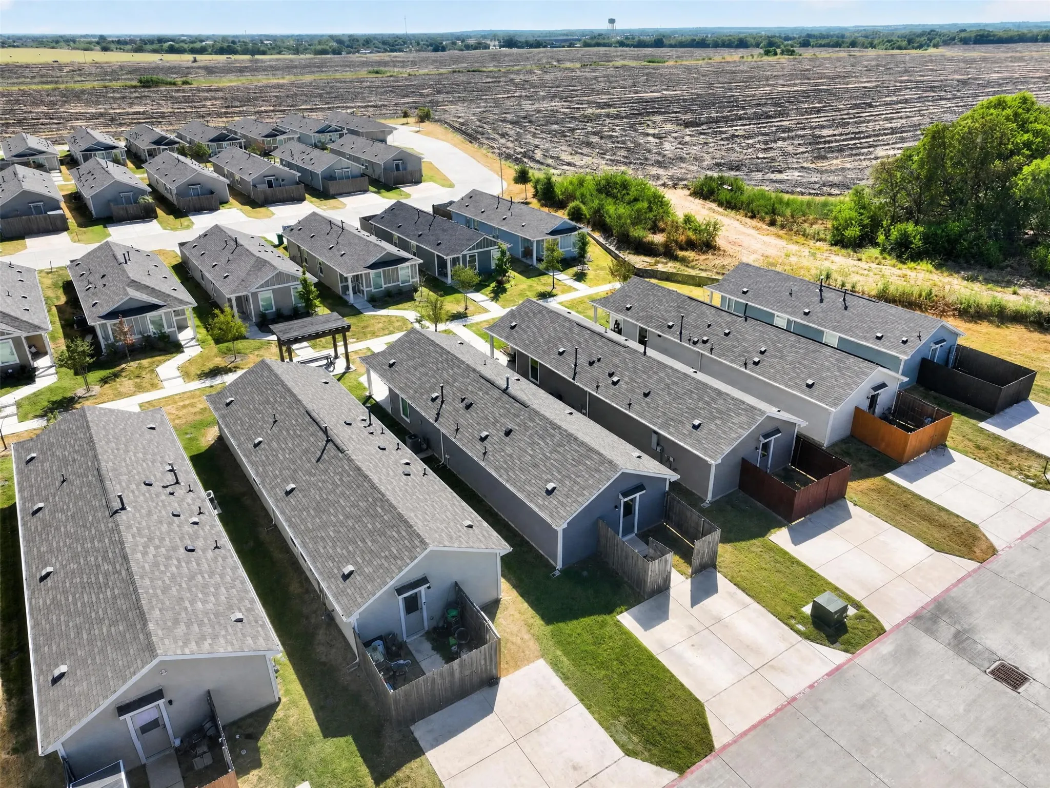 New construction properties featuring a uniform design, individual fenced outdoor spaces, and paved driveways