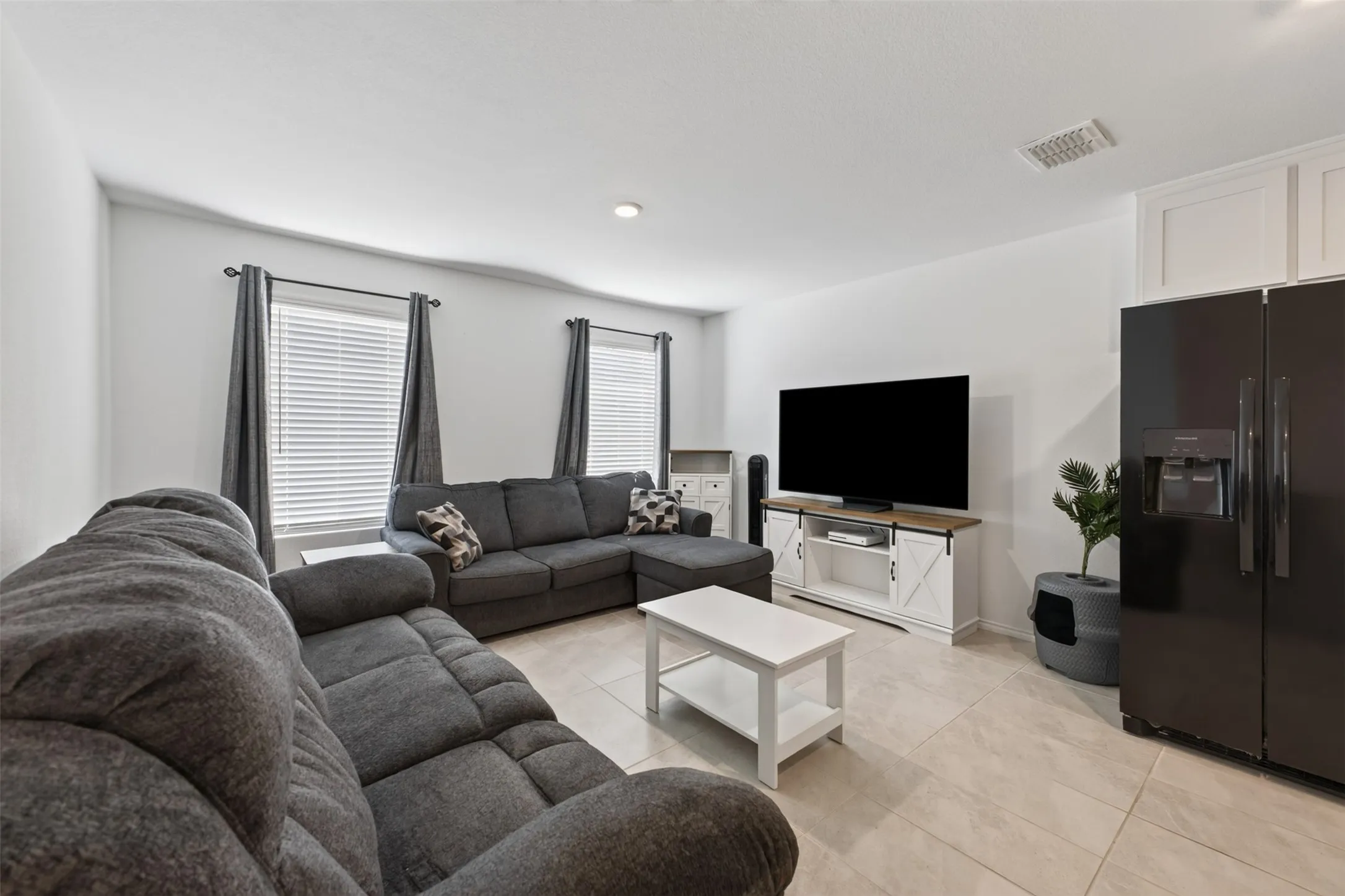 Ceramic tile flooring, dual windows with blinds, recessed lighting, and built-in cabinetry above the refrigerator