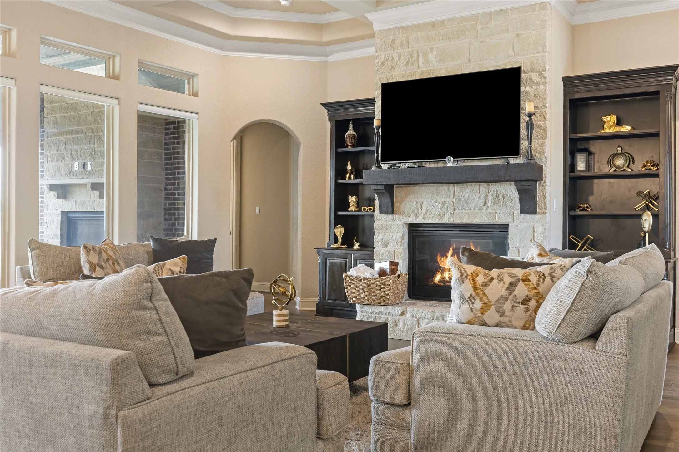 Stone-clad fireplace with dark wood mantel, flanked by built-in shelving and cabinetry