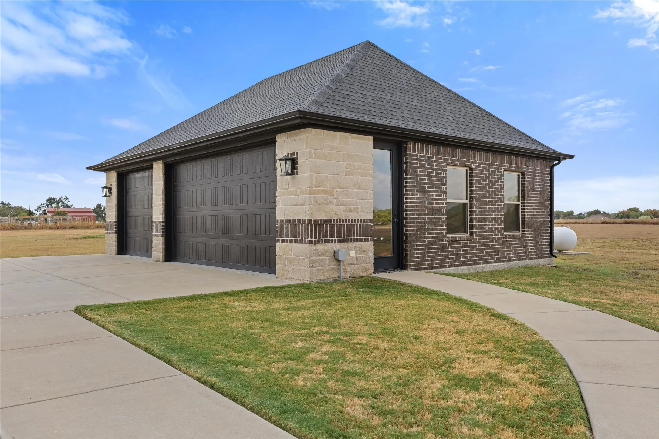 Brick and stone exterior, dual garage doors, concrete driveway, concrete pathway, asphalt shingle roof