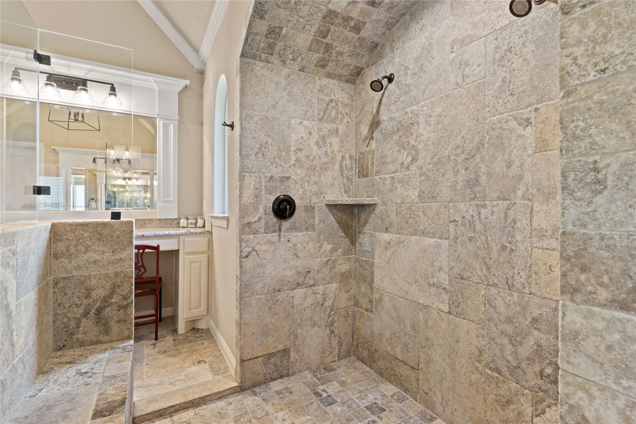 Walk-in shower with natural stone-look tile walls, dual shower heads, and an arched ceiling