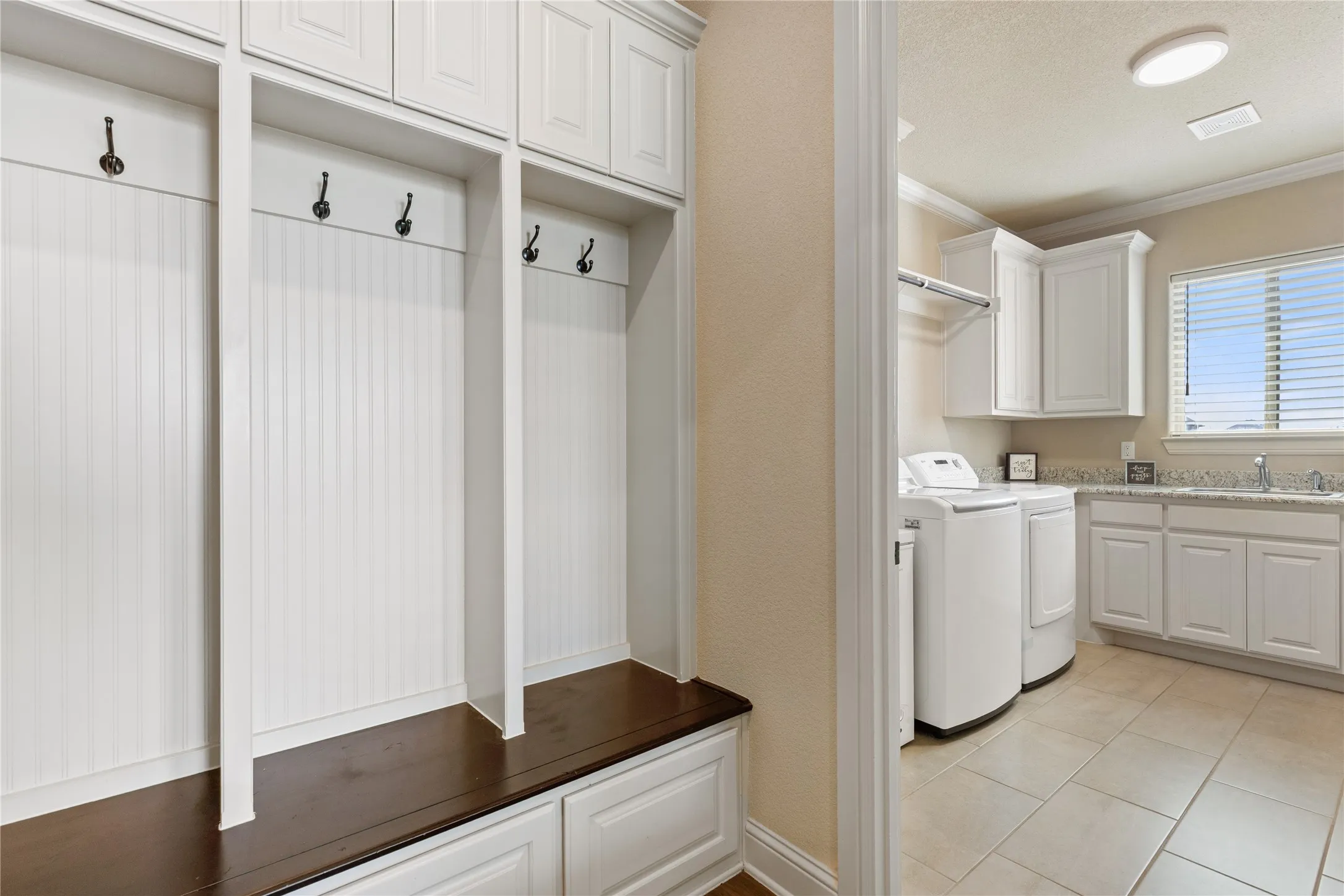 Built-in mudroom storage with bench seating, white cabinetry, and beadboard accents