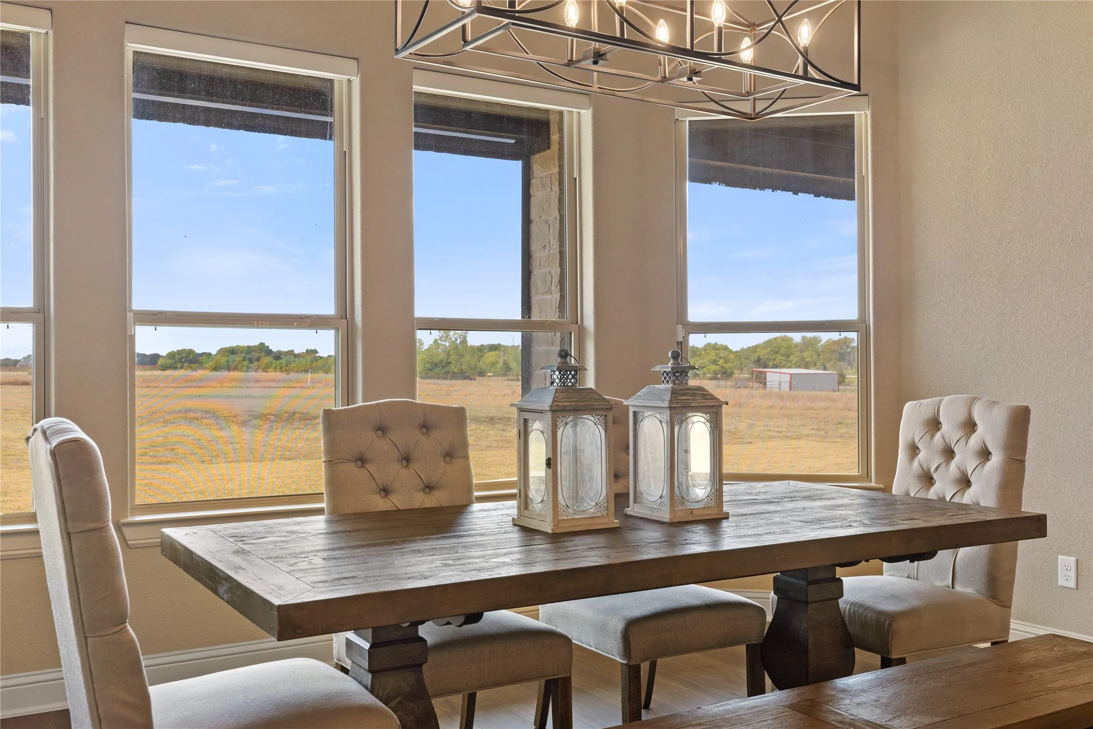 Recessed lighting, rectangular chandelier, multiple windows, light-colored walls, and wood-finish flooring