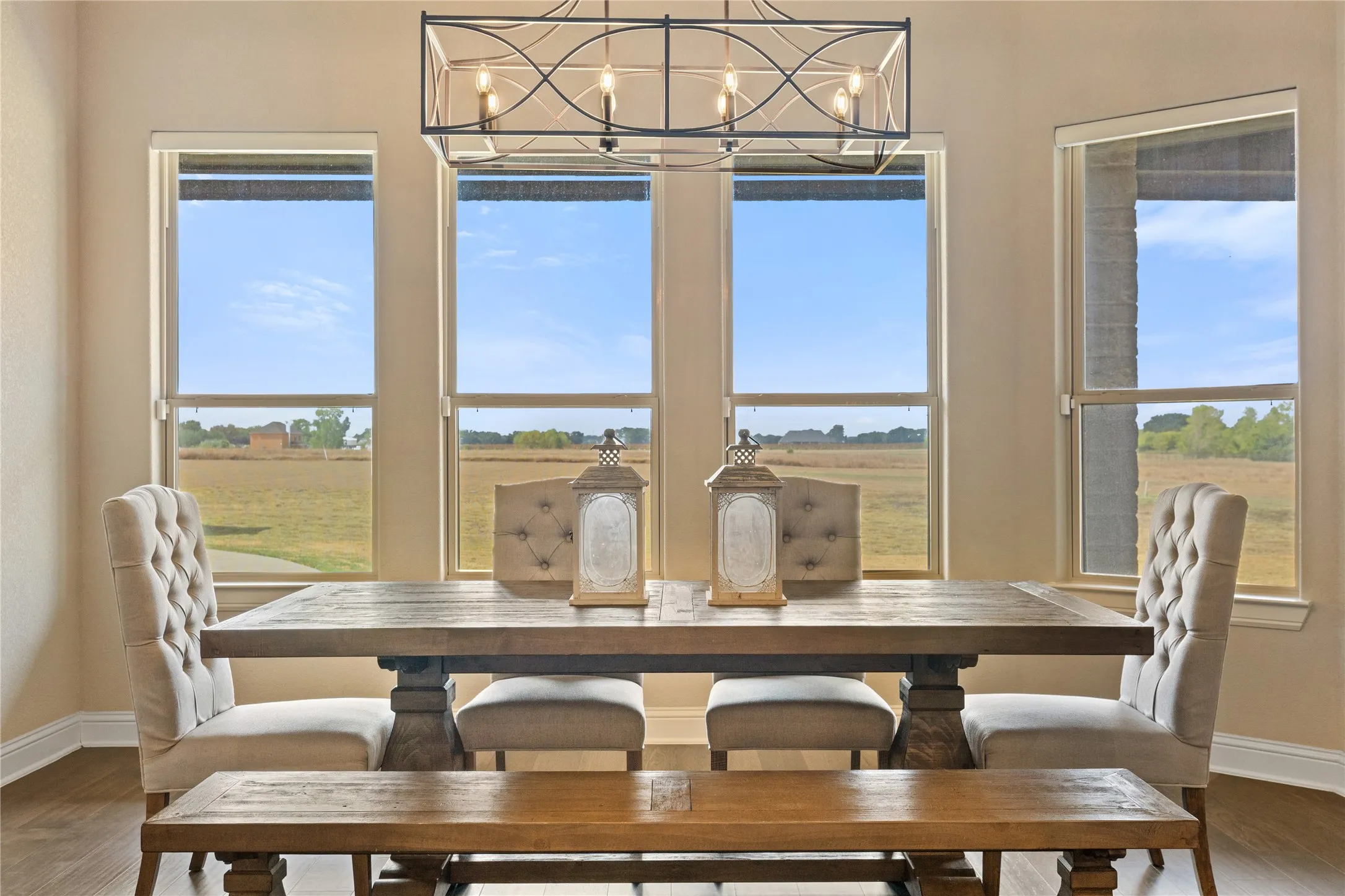 Expansive windows, elegant chandelier, light-toned walls, and wood-finish flooring