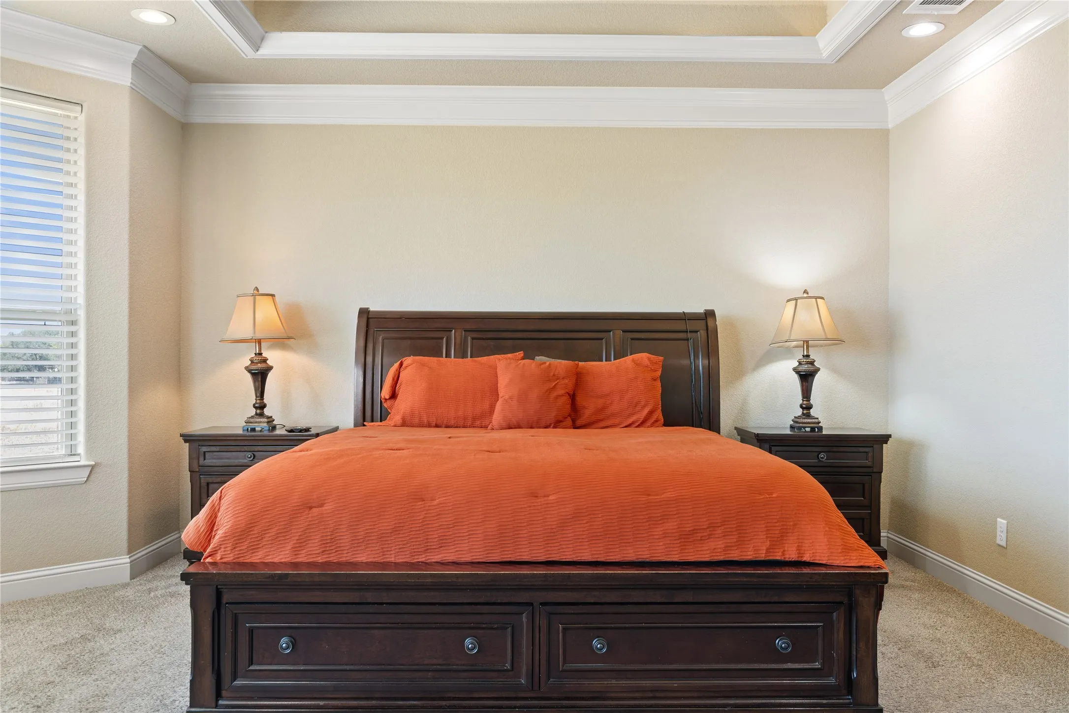 Tray ceiling with recessed lighting, crown molding, double window with blinds, and carpeted flooring