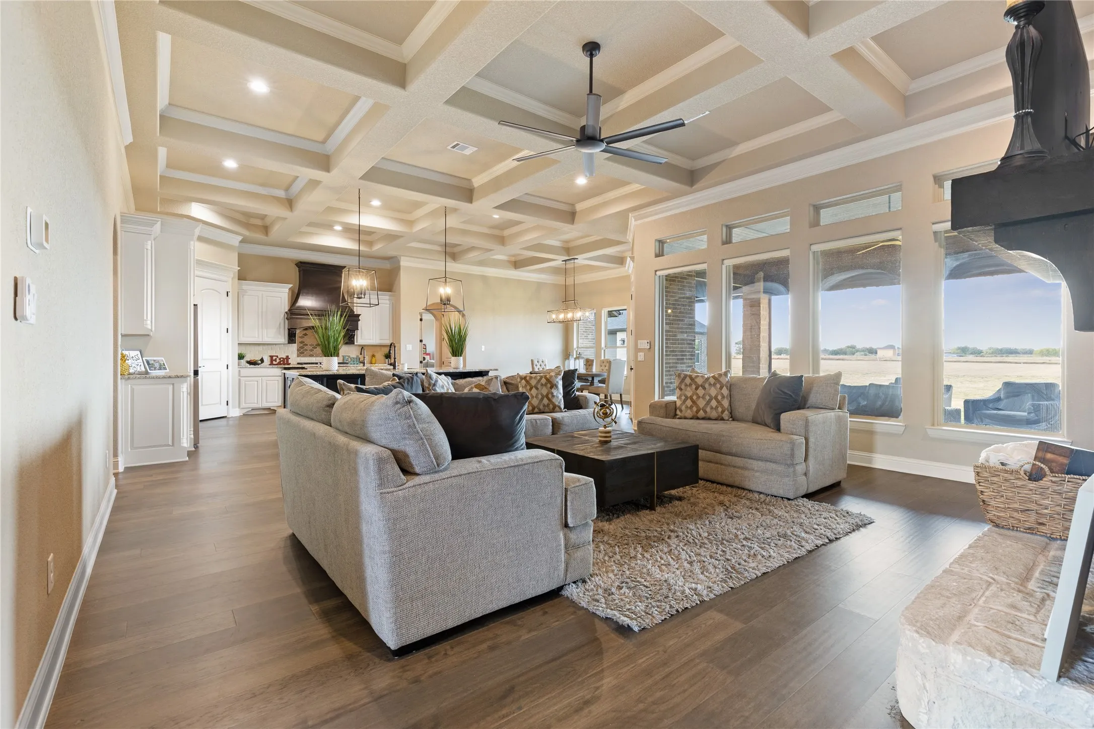 Spacious living area featuring wood-finish flooring, a coffered ceiling with recessed lighting, and large windows