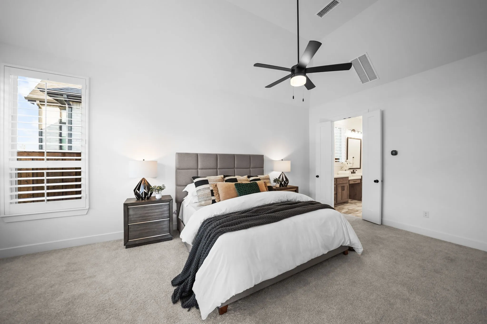 Vaulted ceiling, ceiling fan, white paneled doors, carpet flooring, window with shutters