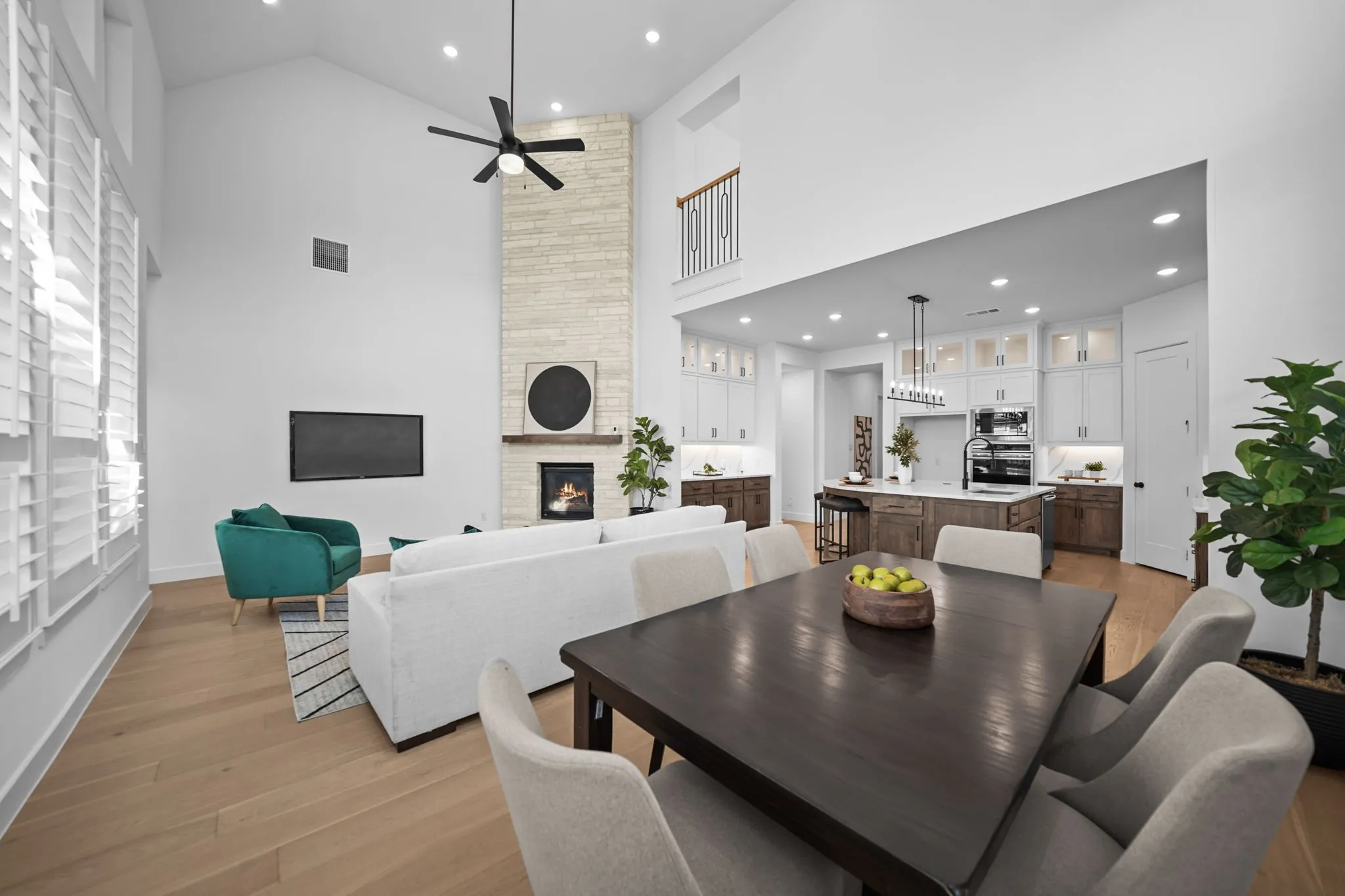 Vaulted ceilings with recessed lighting, light wood-finish flooring, a stone-clad fireplace with a wood mantle, custom kitchen cabinetry, and an oversized kitchen island