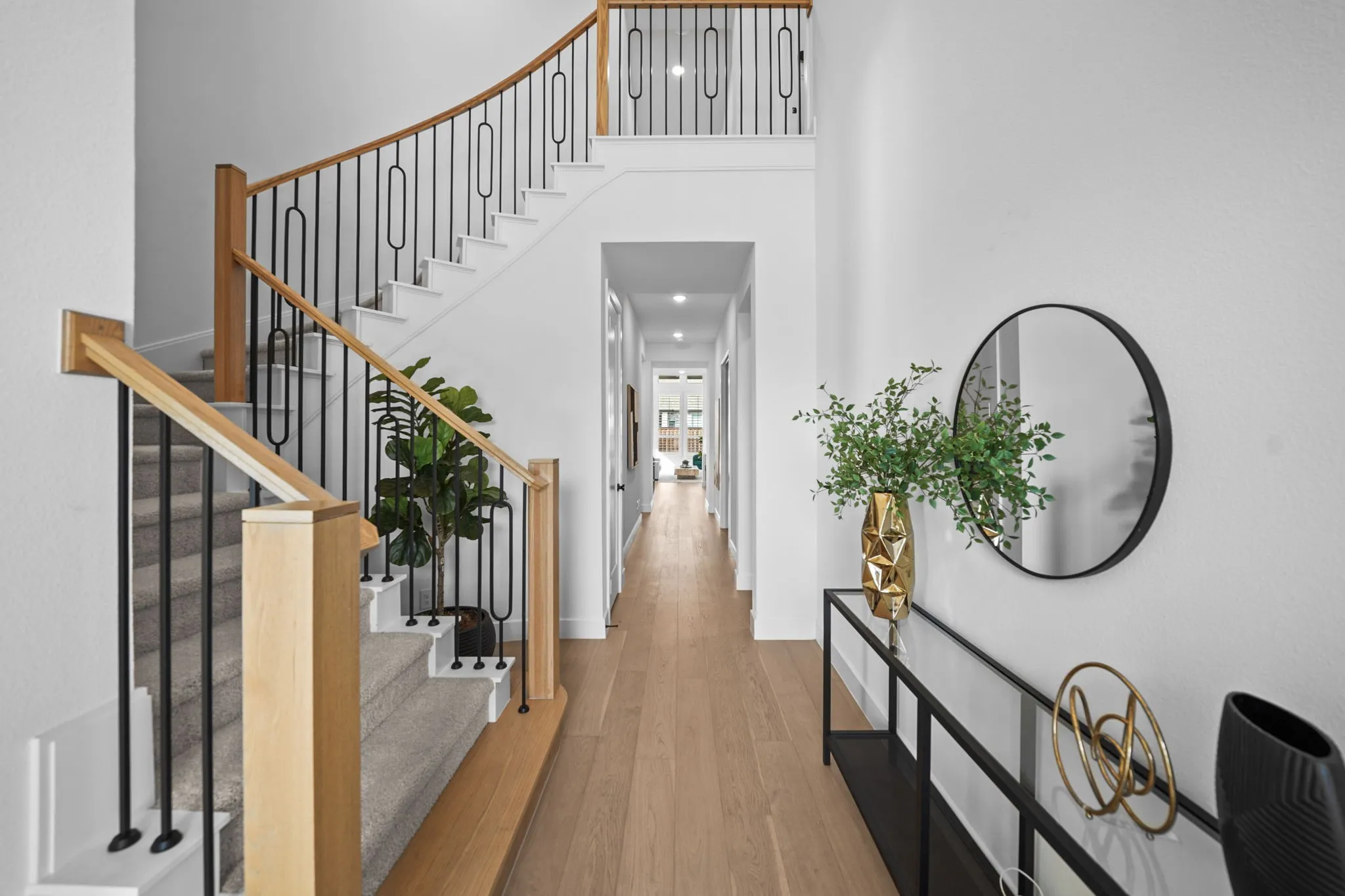 Curved staircase with wood-finish handrails and black metal balusters