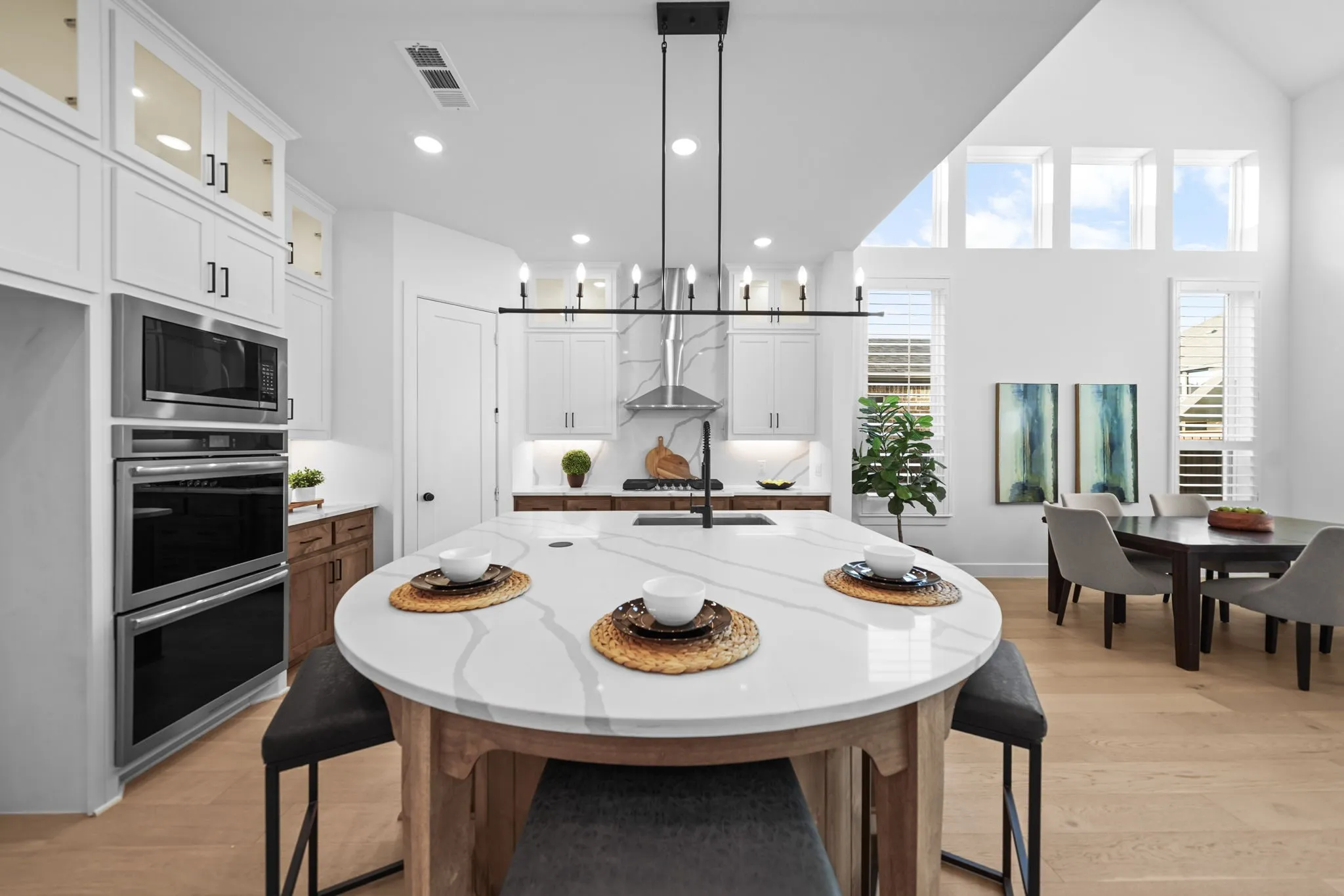 Gourmet kitchen featuring stainless steel double ovens, a built-in microwave, and an expansive island with a waterfall edge