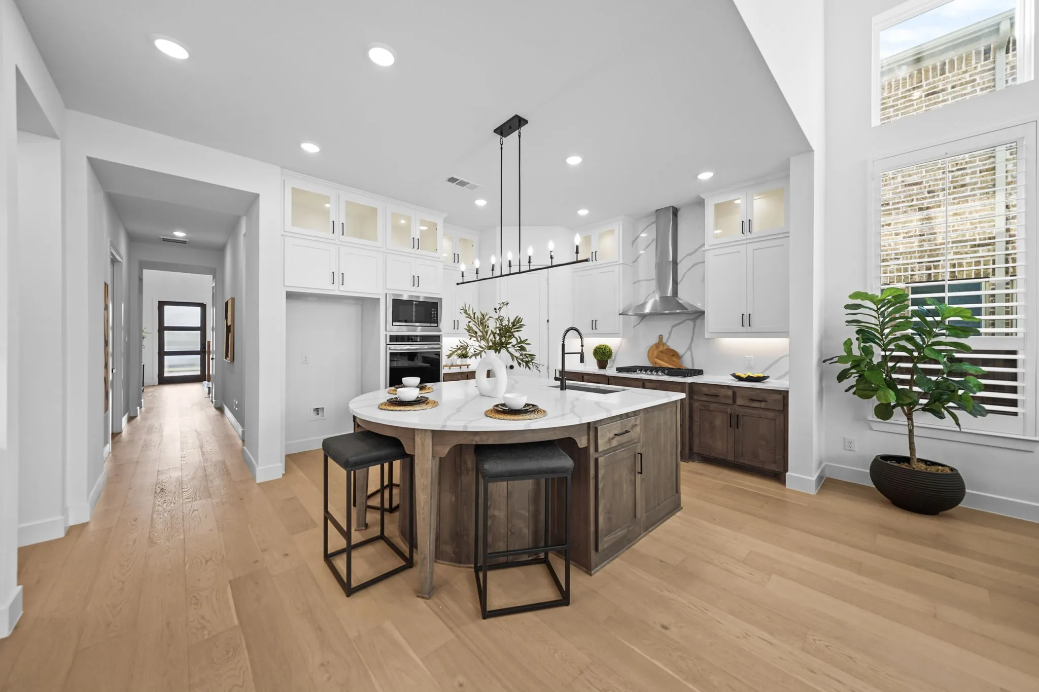 Gourmet kitchen featuring a large central island with seating, integrated stainless steel appliances, stone countertops, and wood-finish flooring