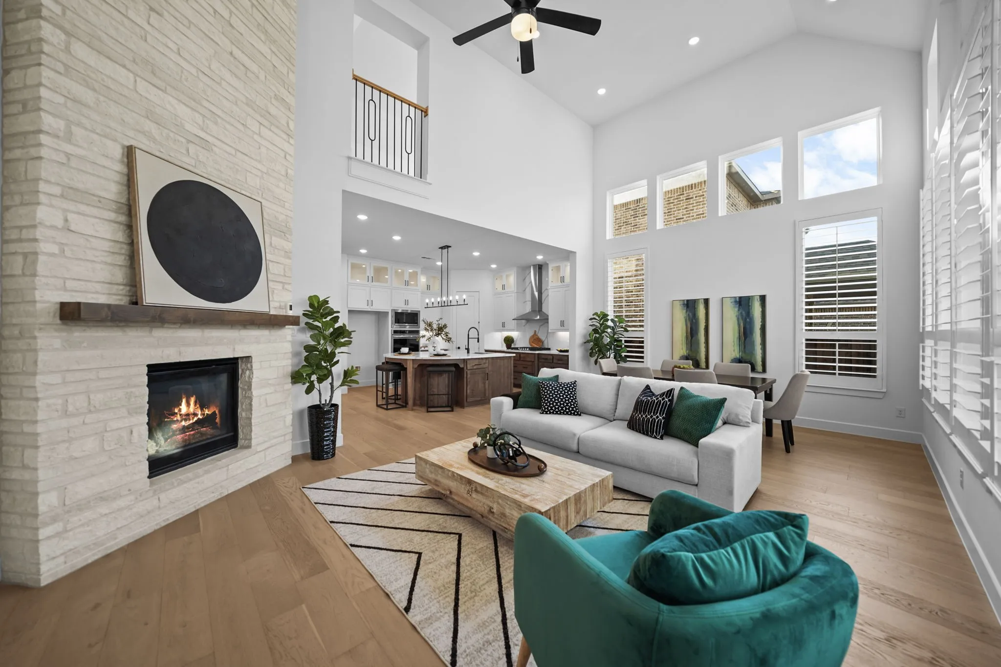 Two-story living area featuring wood-finish flooring, a stone-clad fireplace with a wood mantle, and high ceilings