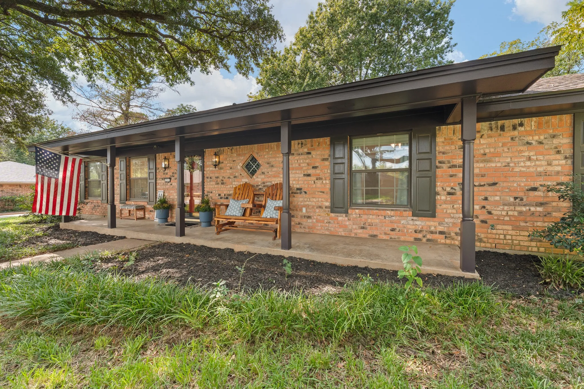 Brick exterior with a covered porch, dark window shutters, and an accent diamond window