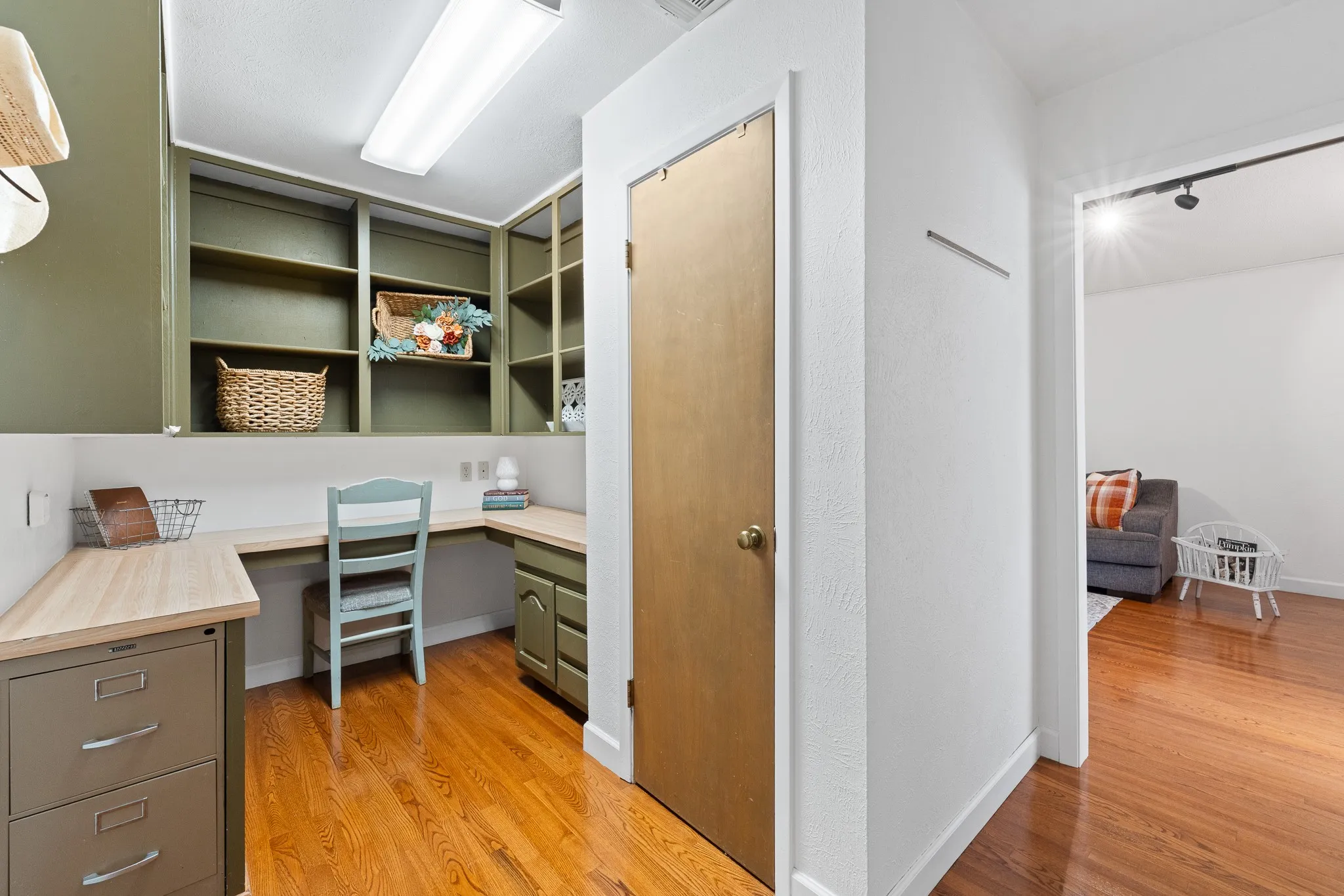 Built-in desk with a natural wood-finish countertop, integrated shelving, and warm wood flooring