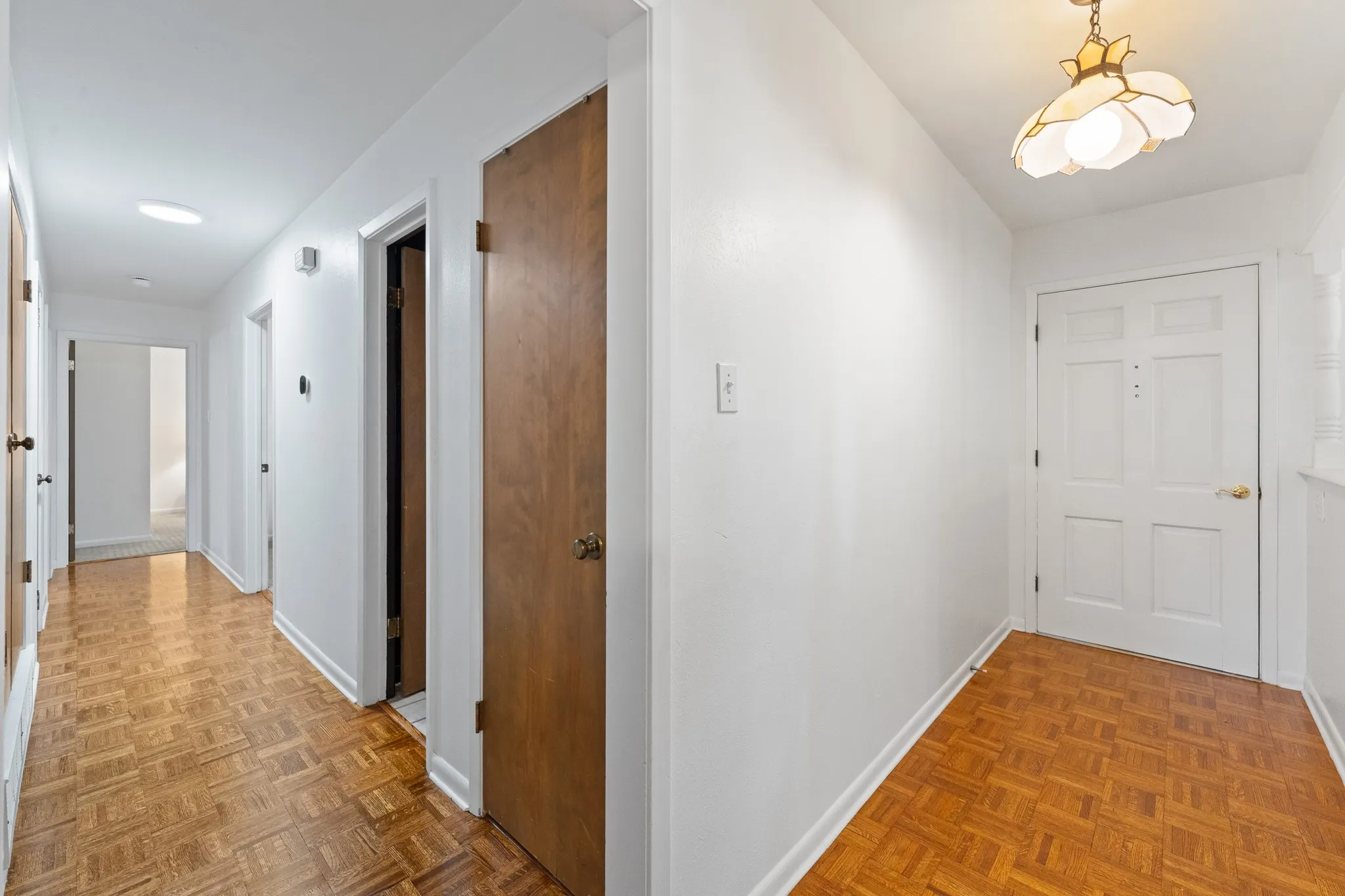 Parquet wood flooring throughout the hallway and entry