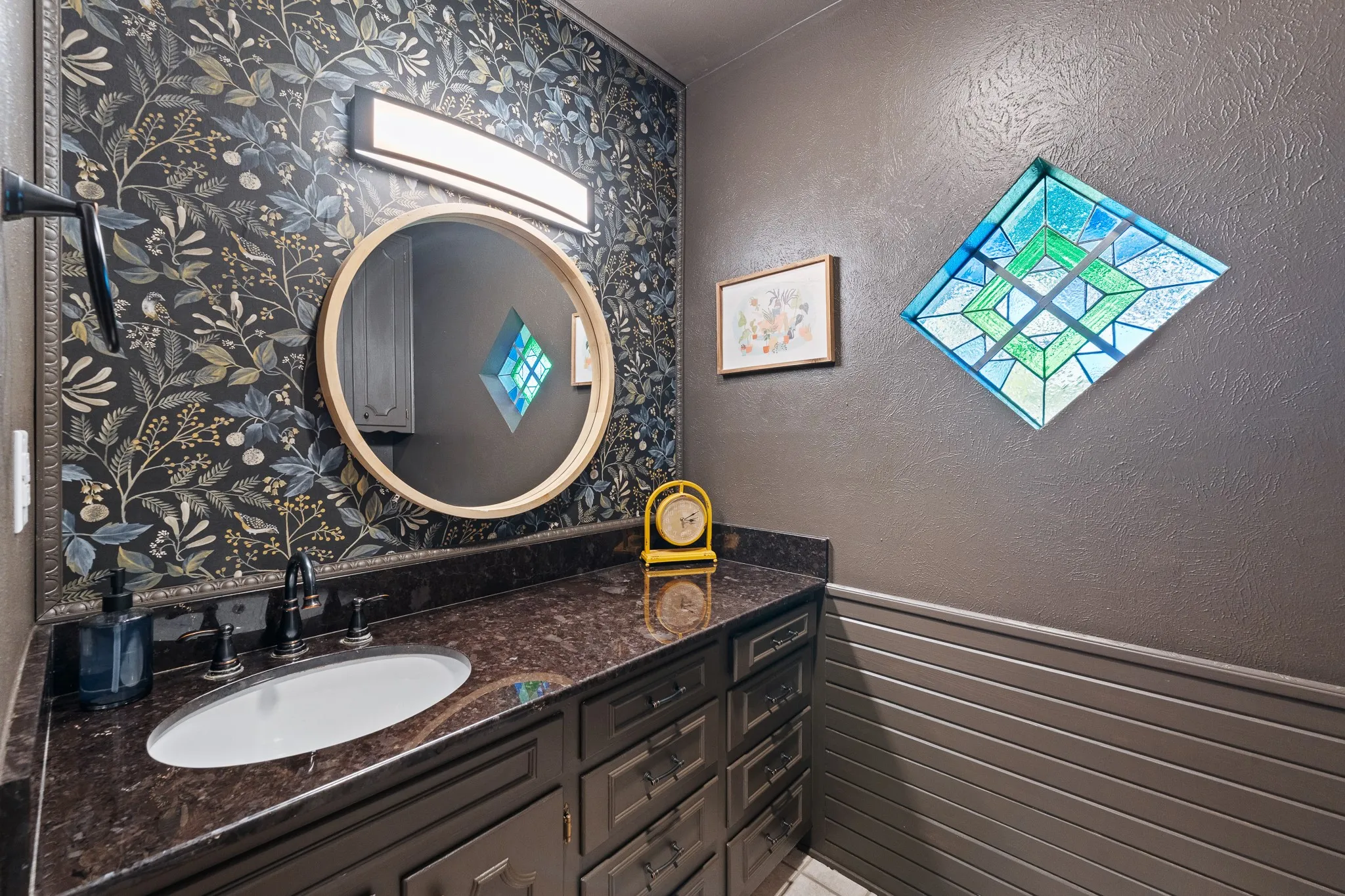 Vanity with an integrated sink, dark countertop, and dark cabinetry