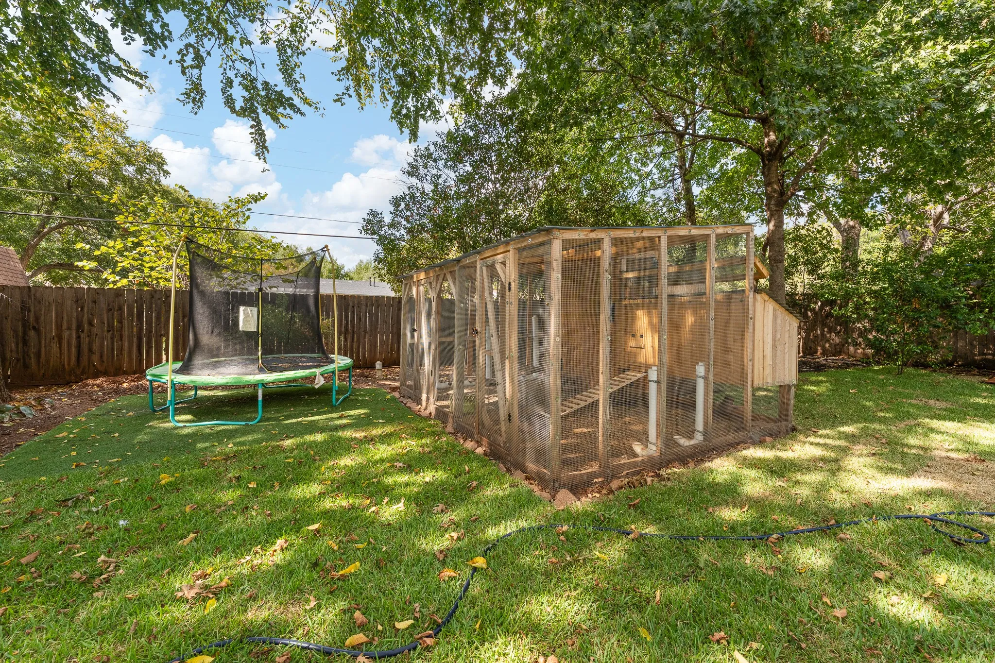 Expansive backyard featuring a manicured lawn, established trees, and a wooden privacy fence