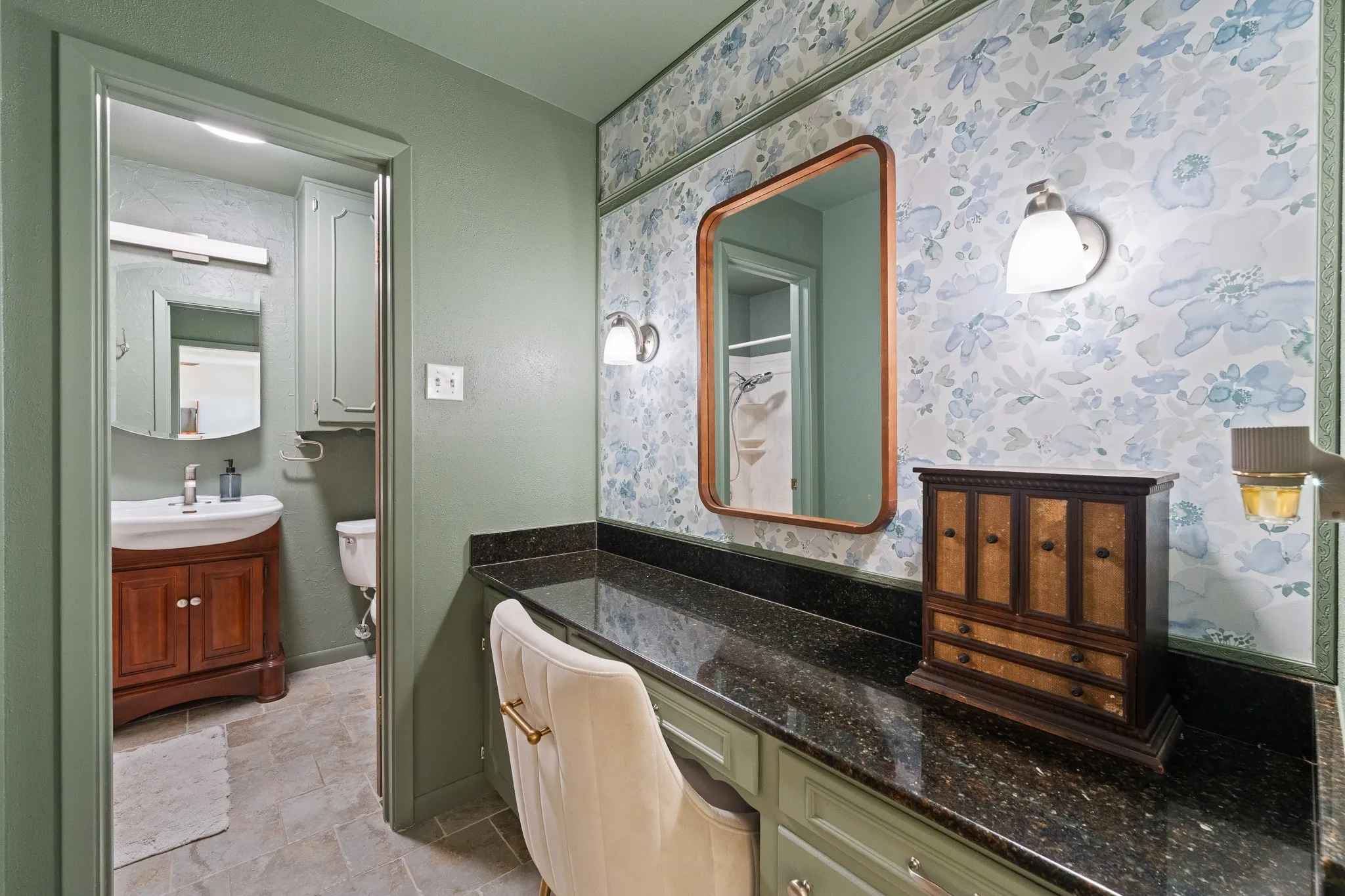 Built-in vanity with a dark speckled countertop, wall-mounted mirror, and sconce lighting