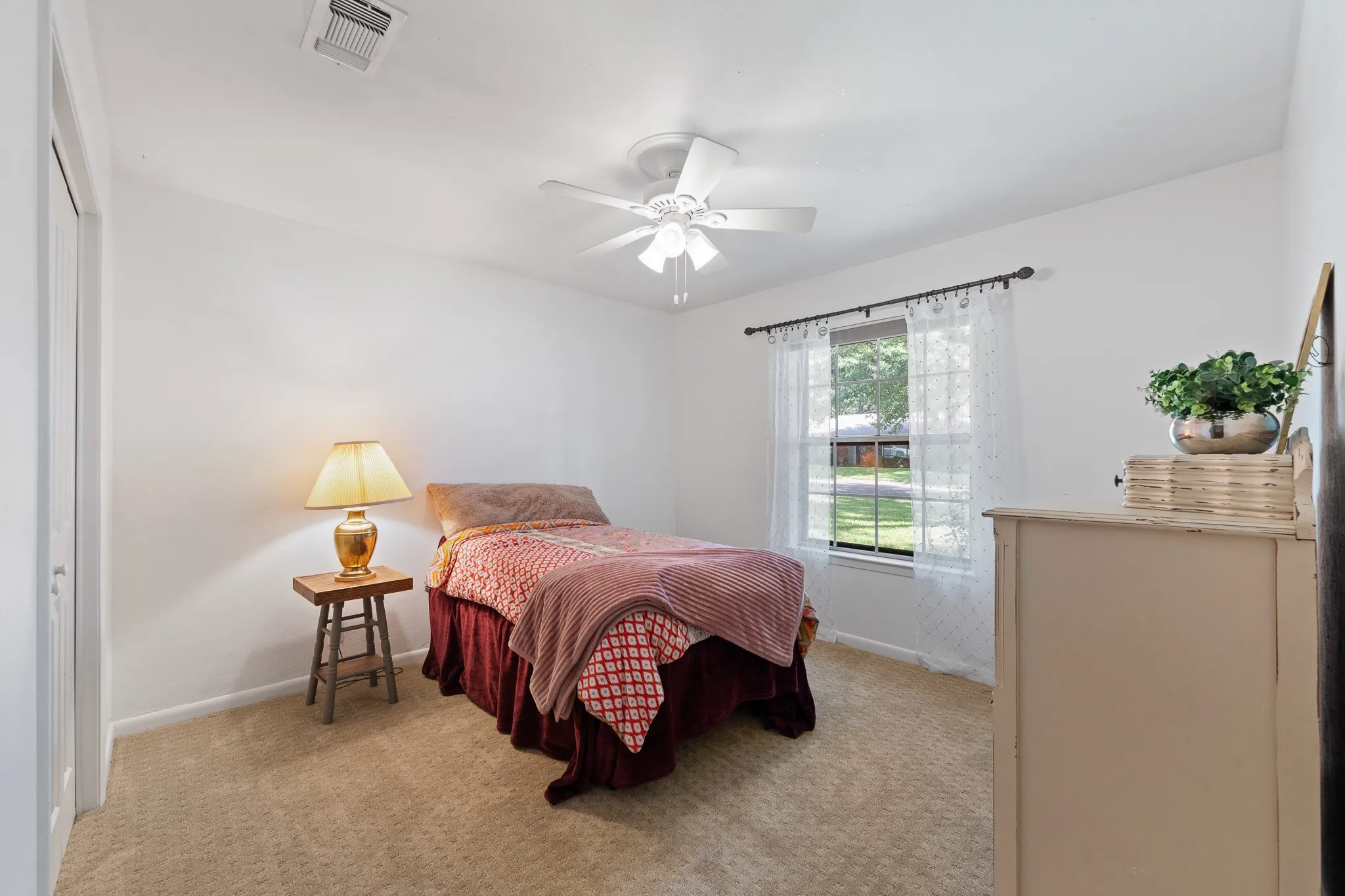 Neutral tone wall paint, window with natural light, ceiling fan, and carpeted flooring