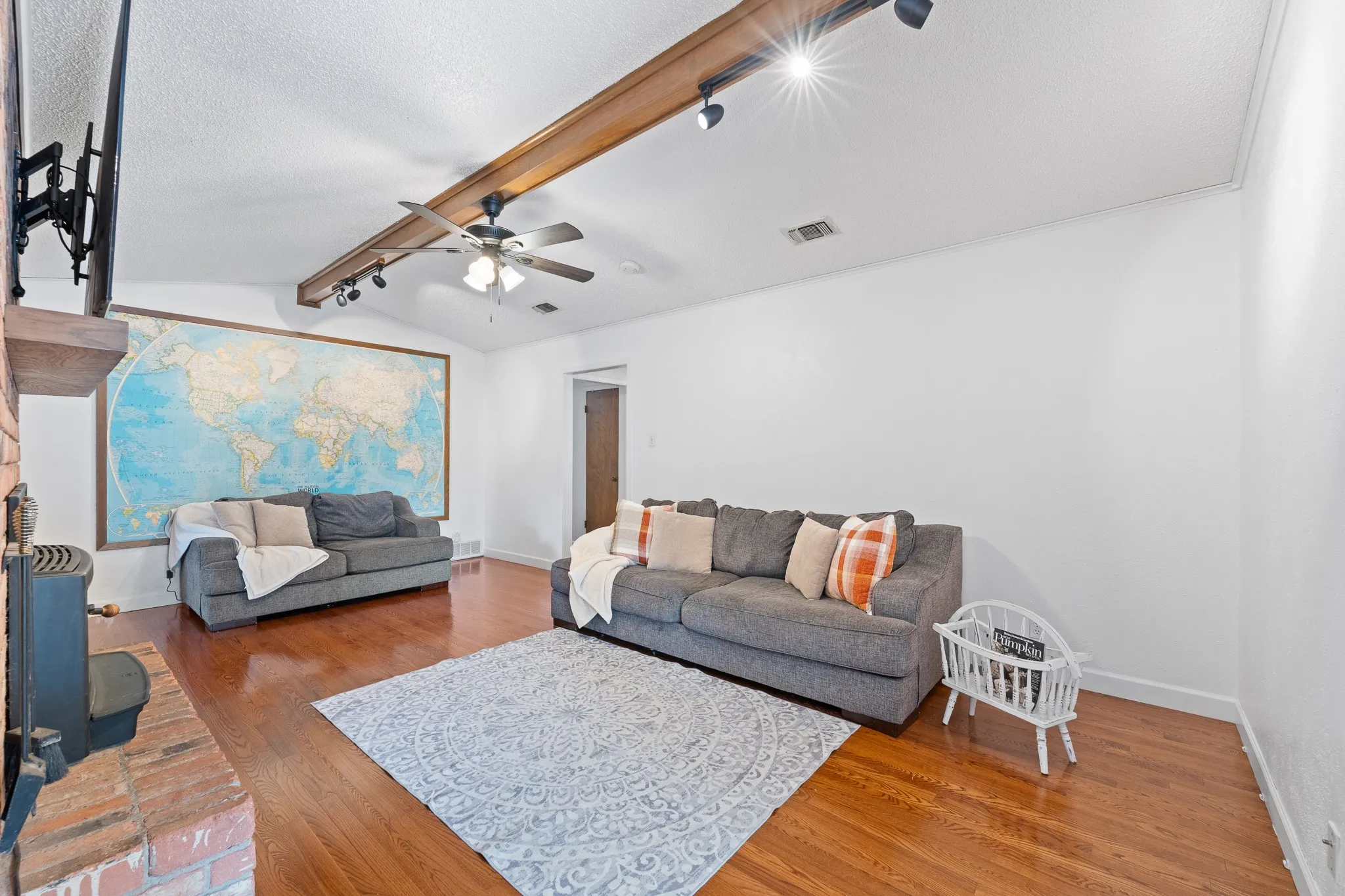 Vaulted ceiling with exposed wood beam, recessed lighting, ceiling fan, wood-finish flooring, and a brick fireplace
