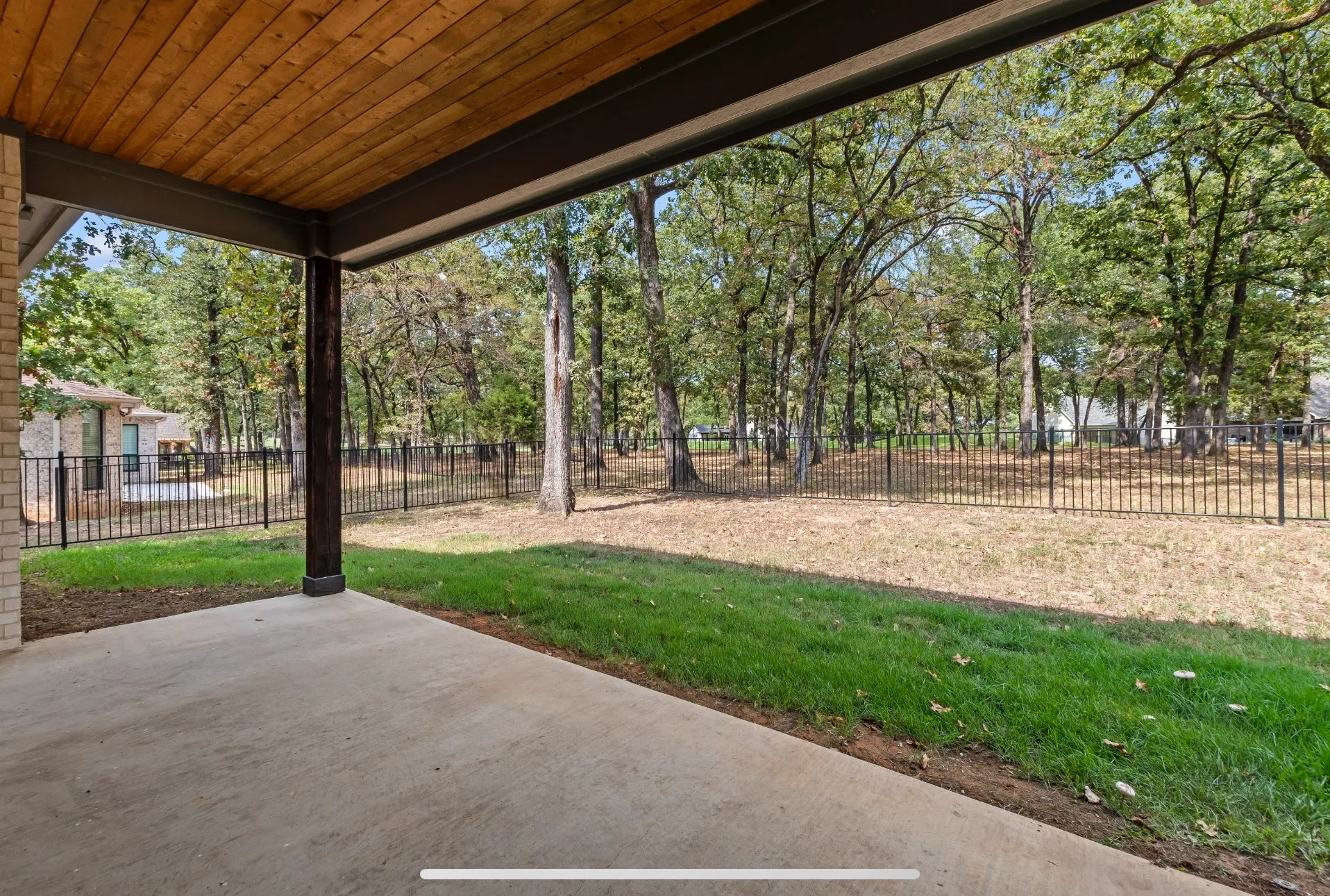 Expansive covered patio with a wood-finish ceiling, exposed beam, and concrete flooring