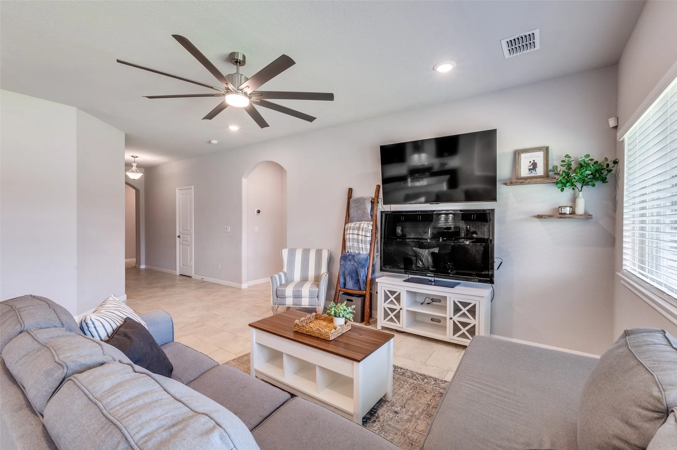 Spacious living area featuring a ceiling fan with integrated lighting, recessed lighting, tile flooring, and a window with blinds